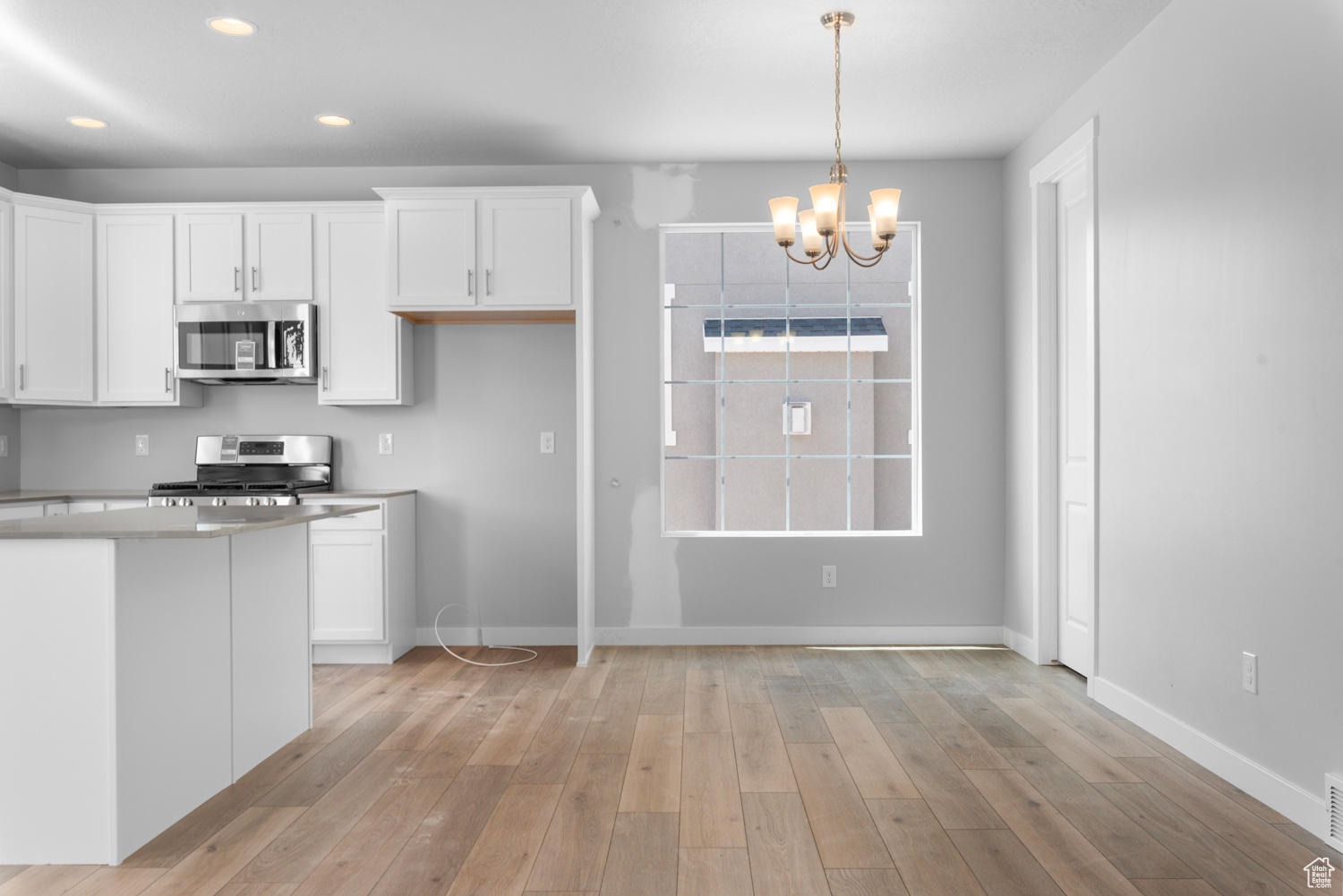 Kitchen with white cabinets, light hardwood / wood-style flooring, and range