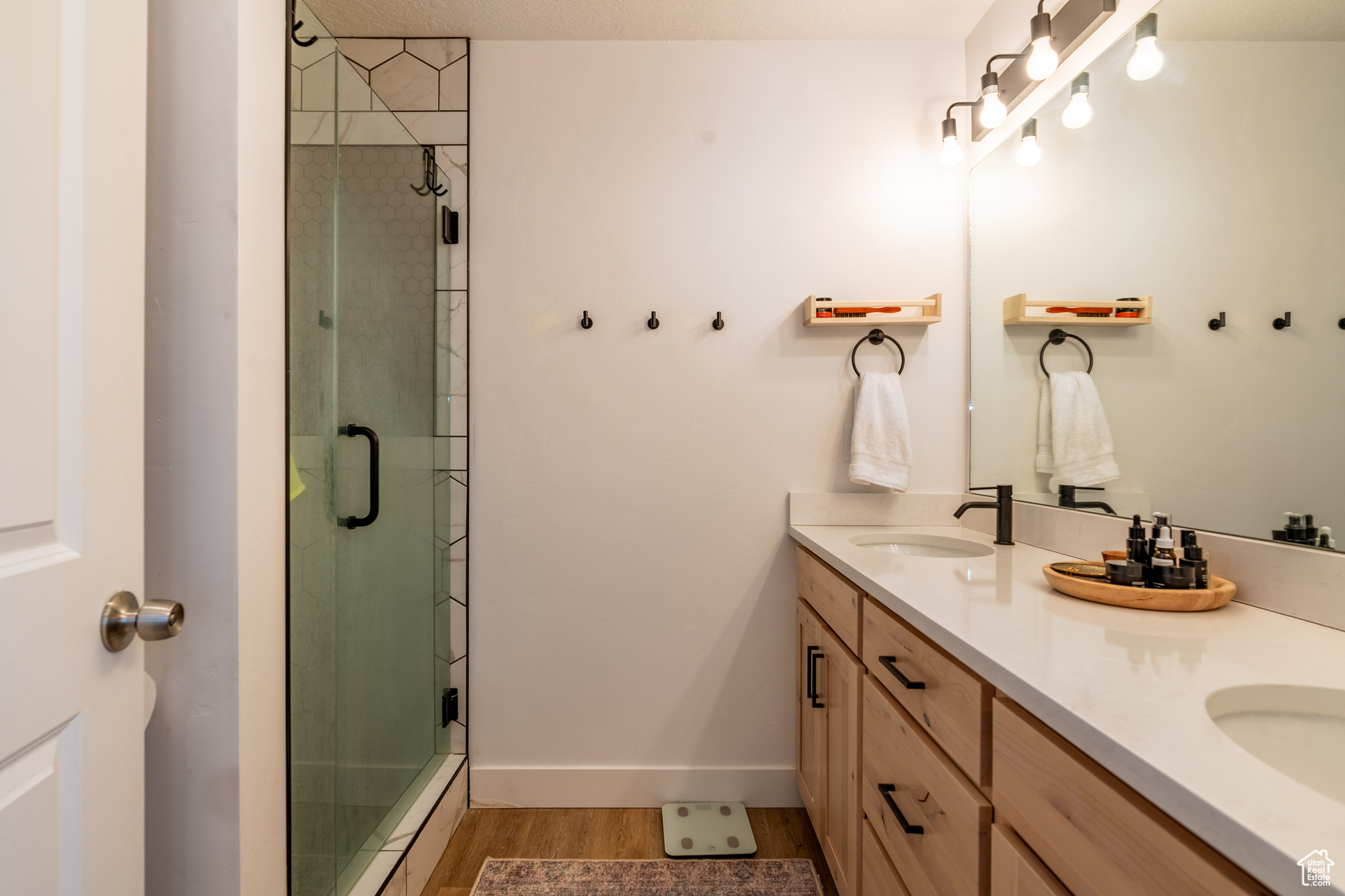 Bathroom featuring walk in shower, dual vanity, and wood-type flooring