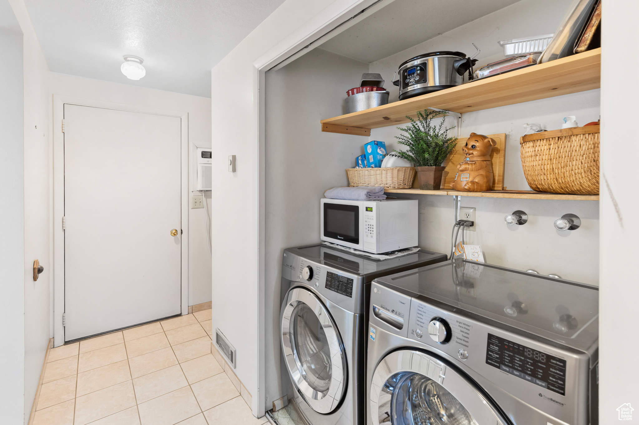 Clothes washing area with washer and clothes dryer and light tile floors