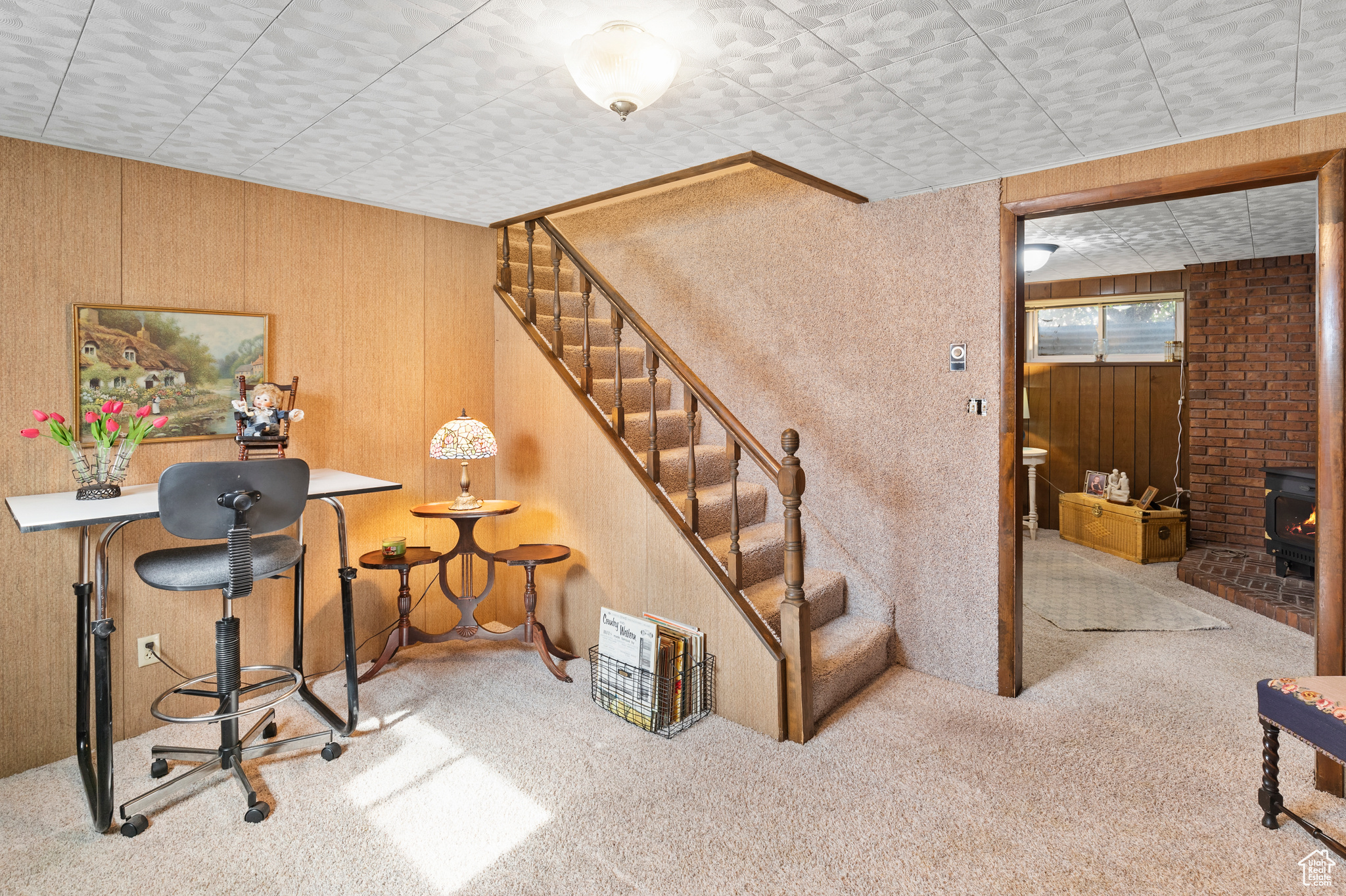 Carpeted office featuring brick wall, wooden walls, and a wood stove