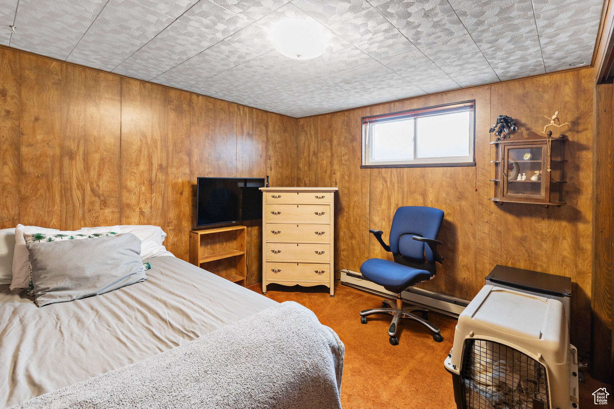 Carpeted bedroom with baseboard heating and wooden walls