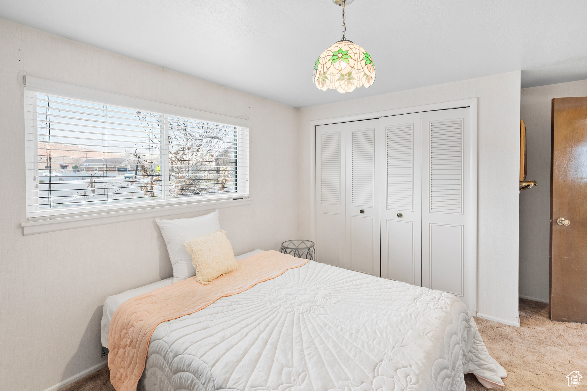 Bedroom with light colored carpet and a closet