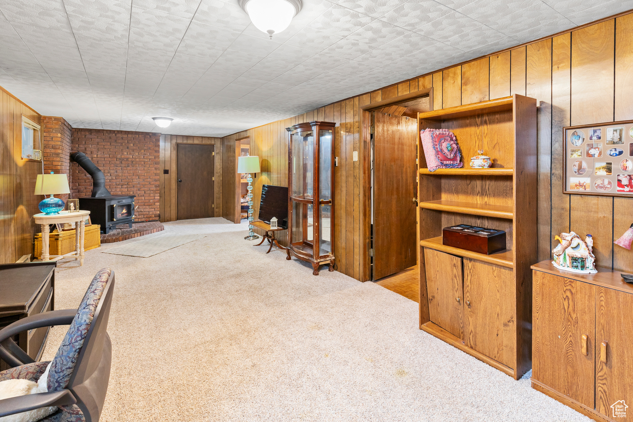 Interior space featuring light carpet, a wood stove, and wooden walls