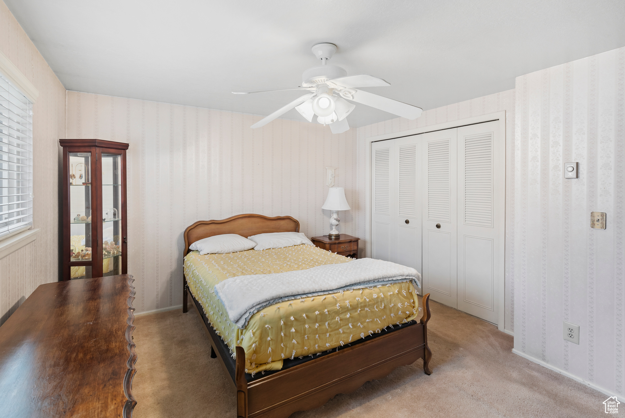 Carpeted bedroom featuring a closet and ceiling fan