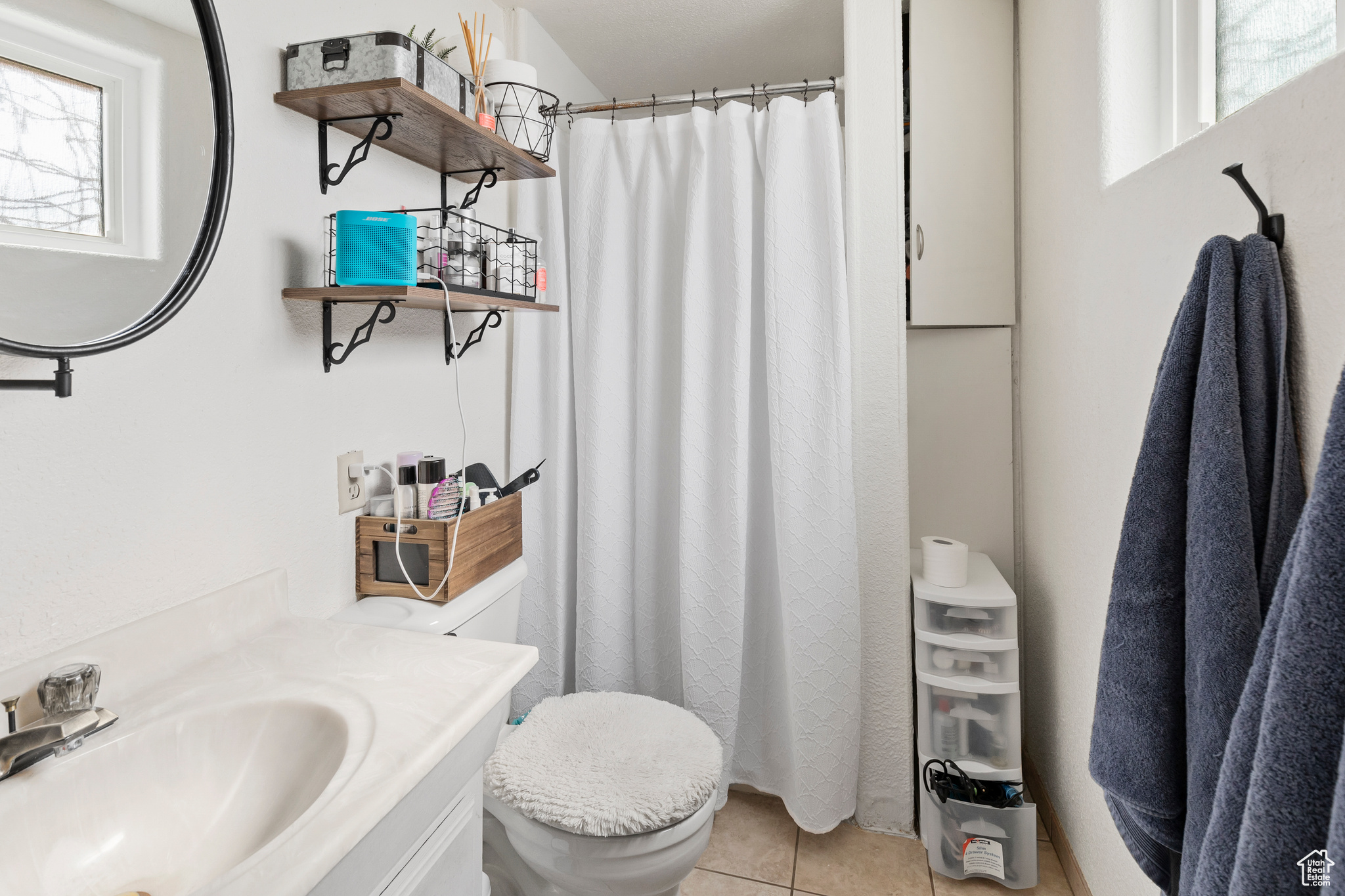 Bathroom with toilet, tile flooring, large vanity, and a healthy amount of sunlight