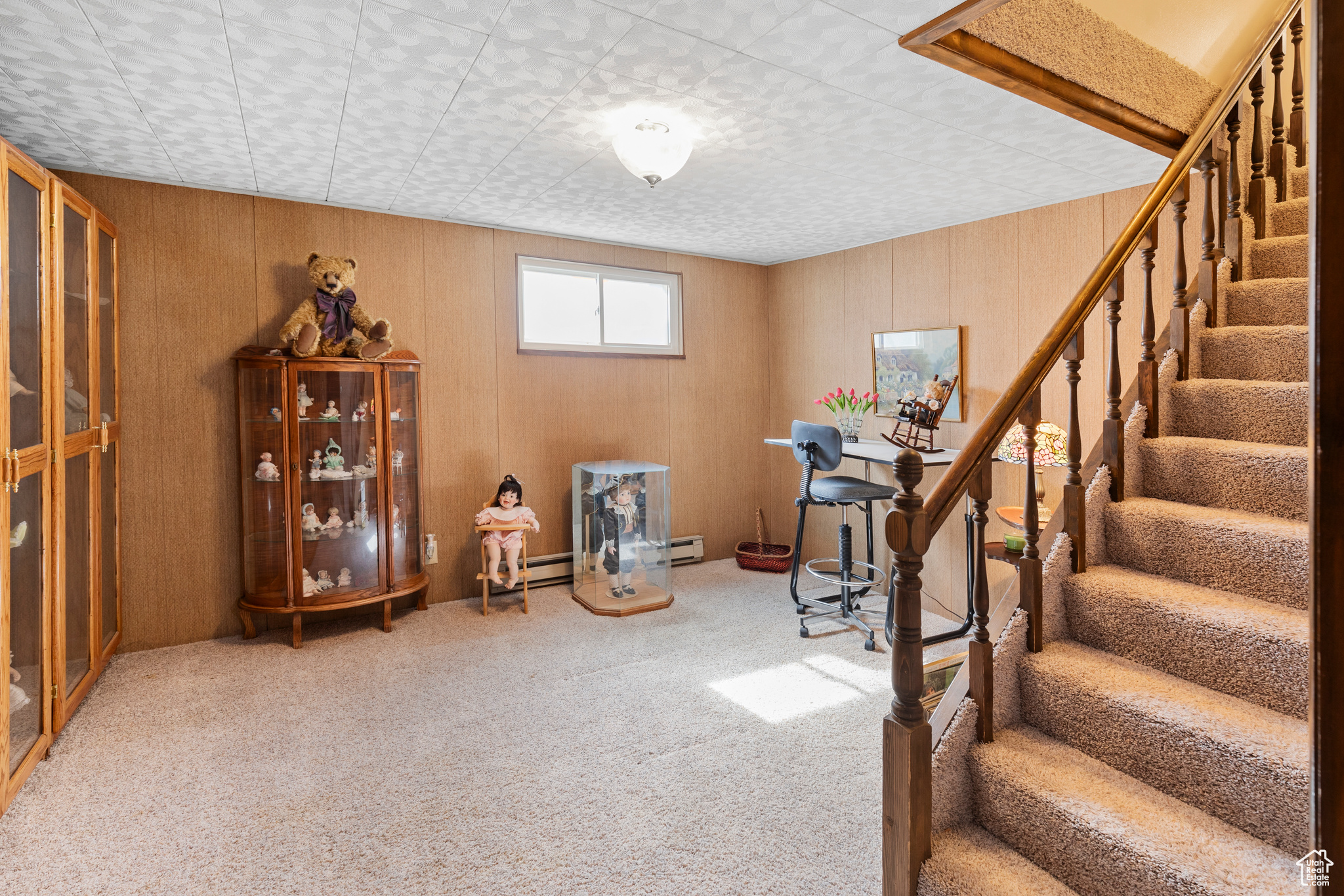 Entryway with baseboard heating, wood walls, and light colored carpet