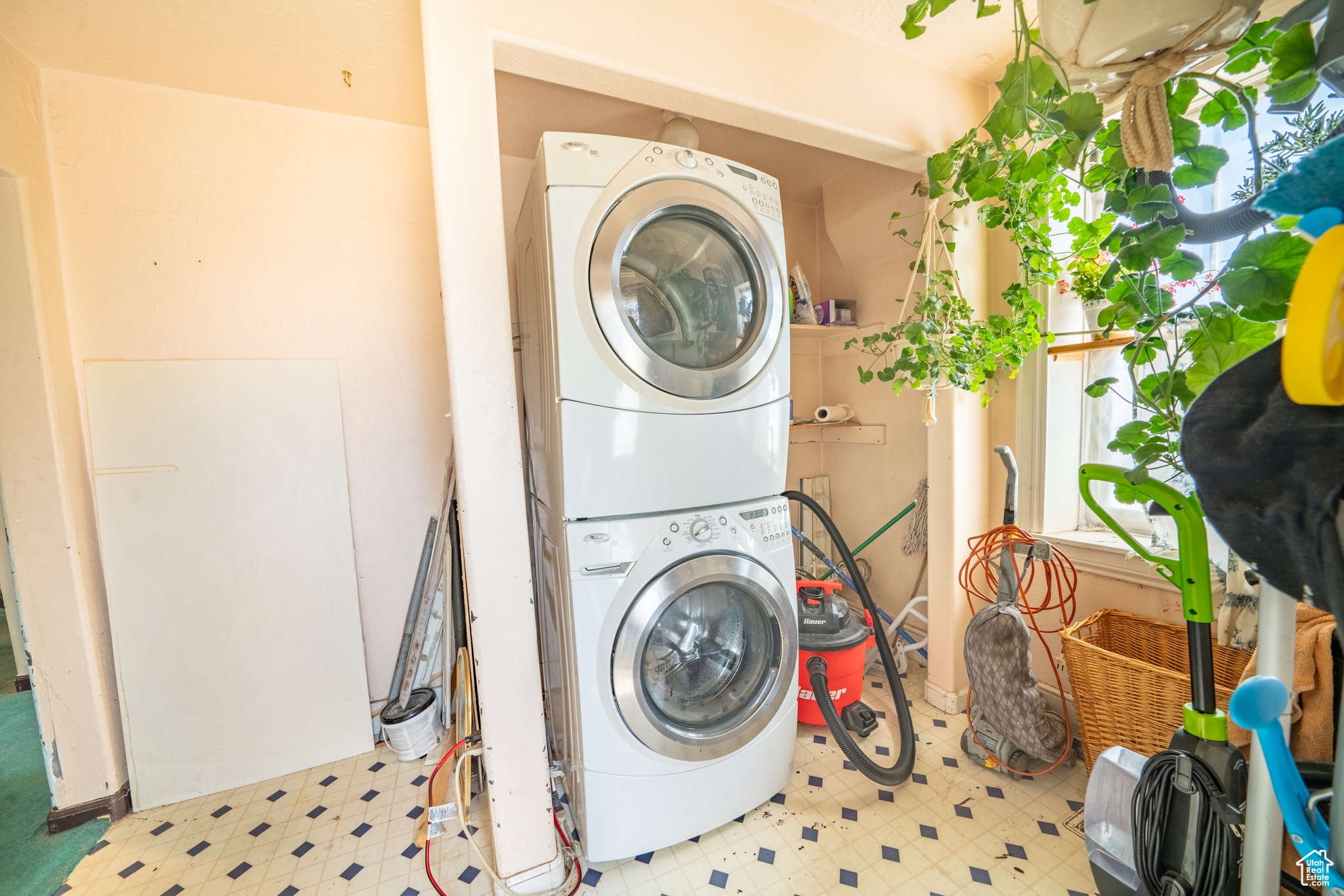 Laundry room featuring light tile flooring and stacked washer and dryer