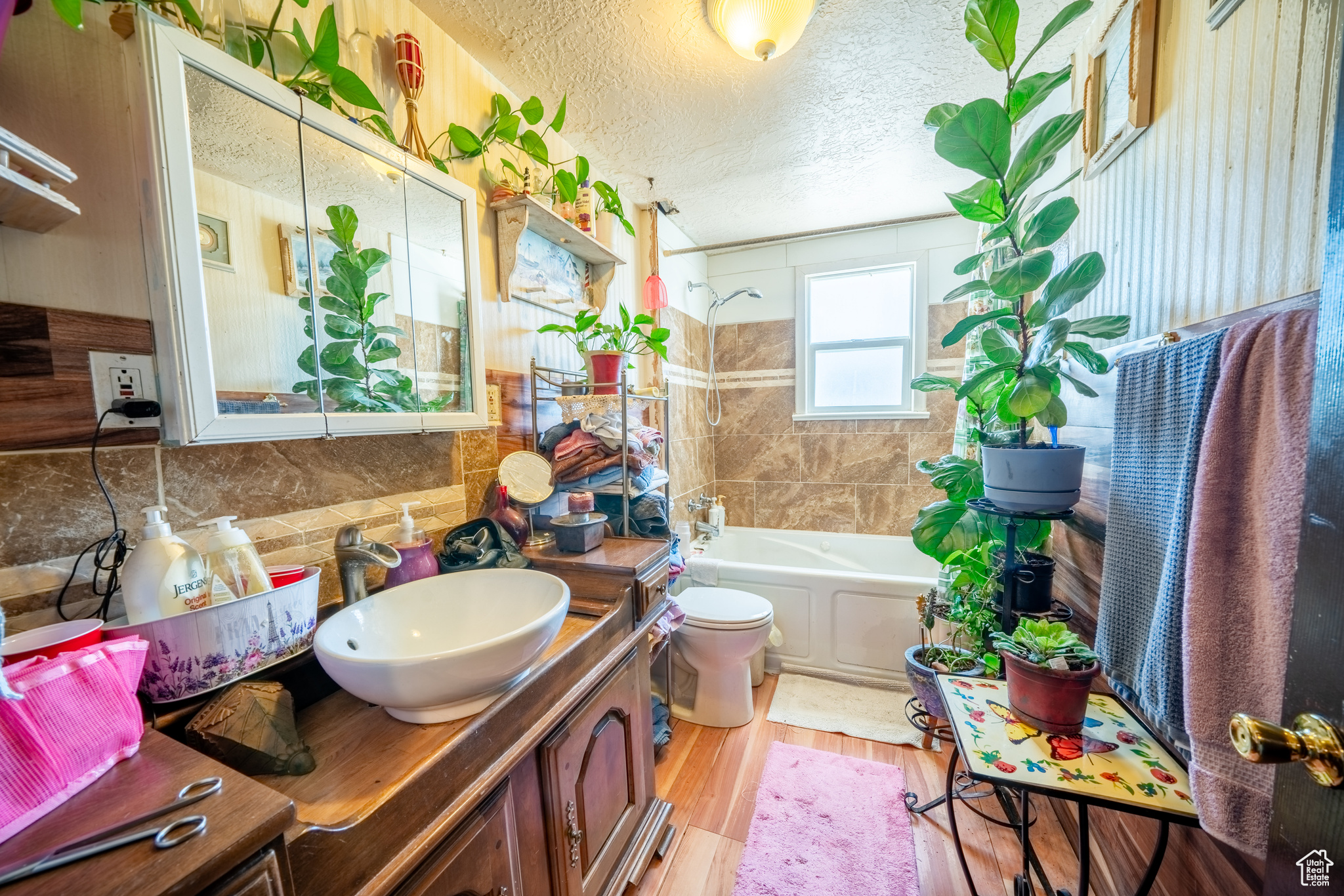 Full bathroom with hardwood / wood-style flooring, vanity, tiled shower / bath combo, a textured ceiling, and toilet