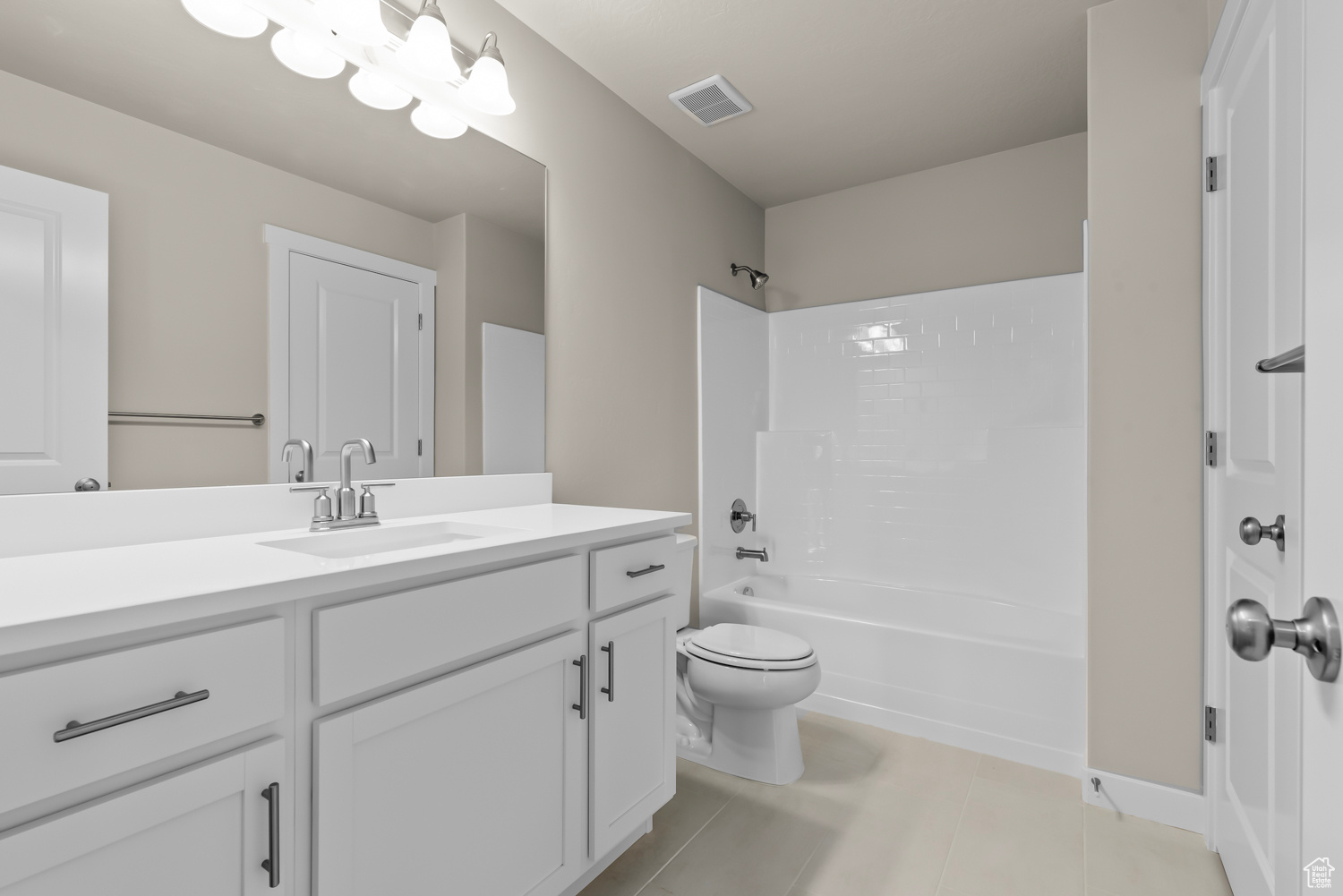 Full bathroom featuring toilet, tile floors, vanity, and washtub / shower combination
