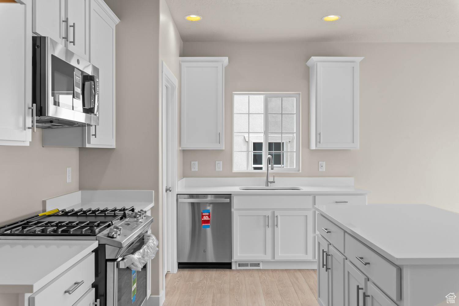 Kitchen featuring white cabinets, sink, appliances with stainless steel finishes, and light wood-type flooring