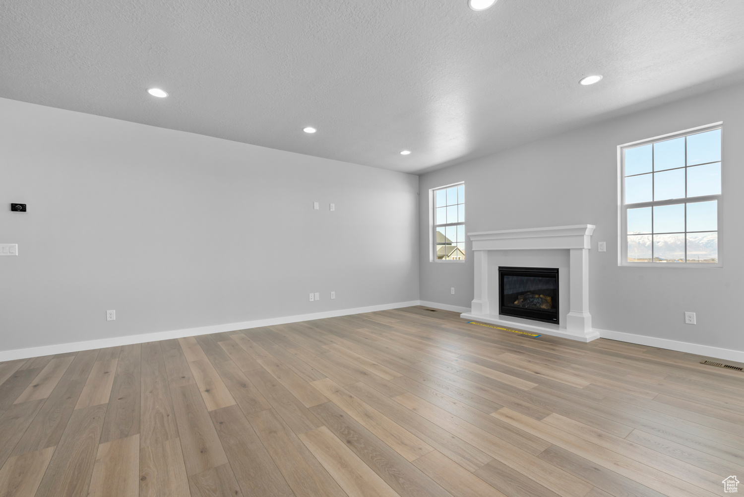 Unfurnished living room featuring a textured ceiling and light hardwood / wood-style flooring