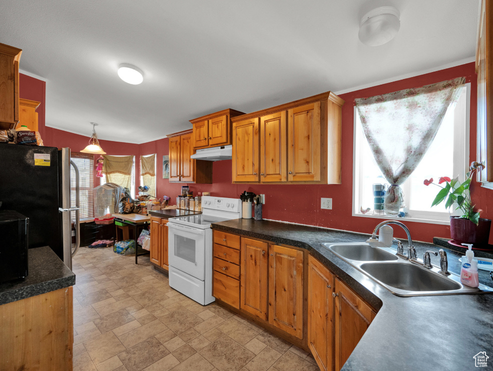 Kitchen with plenty of natural light, white range with electric cooktop, hanging light fixtures, and sink