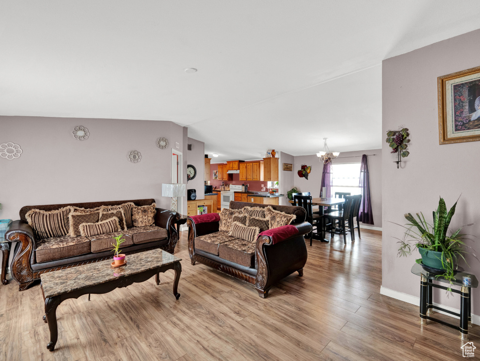 Living room featuring a notable chandelier, light hardwood / wood-style floors, and vaulted ceiling