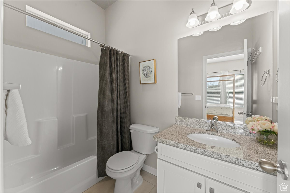 Full bathroom with large vanity, shower / tub combo, toilet, and tile floors
