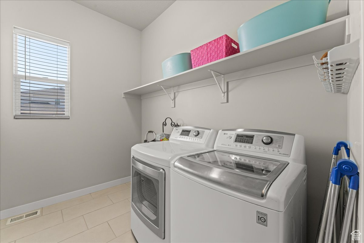 Clothes washing area with separate washer and dryer and light tile flooring