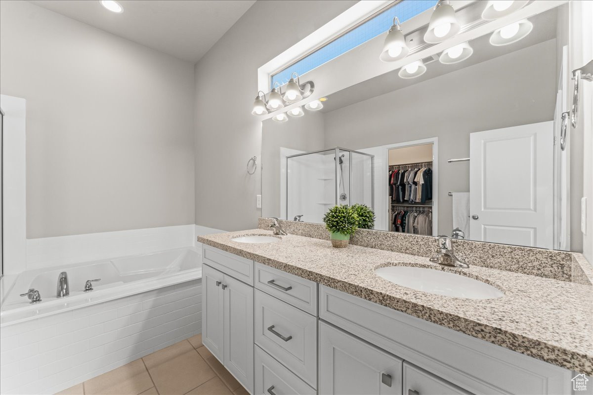 Bathroom featuring dual sinks, tile flooring, tiled tub, and oversized vanity