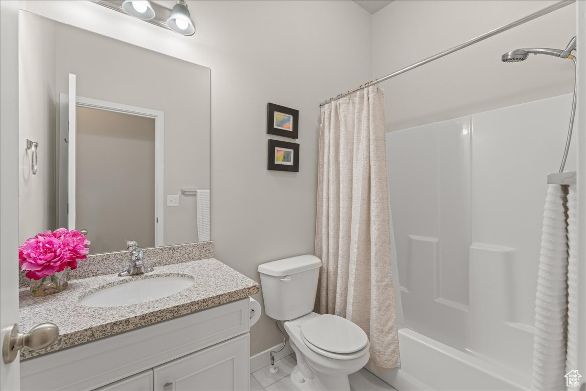 Full bathroom featuring shower / bathtub combination with curtain, tile floors, vanity, and toilet