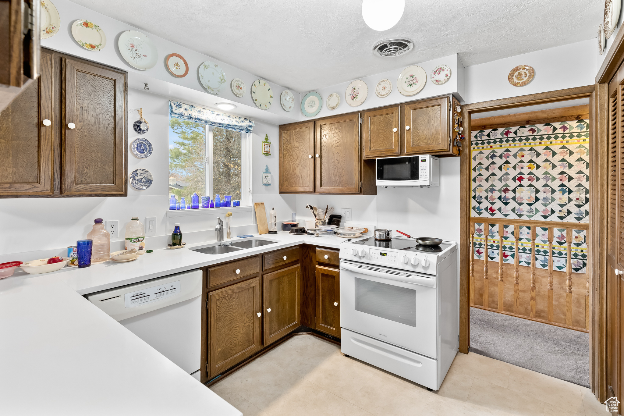 Kitchen featuring sink, white appliances, and light tile floors