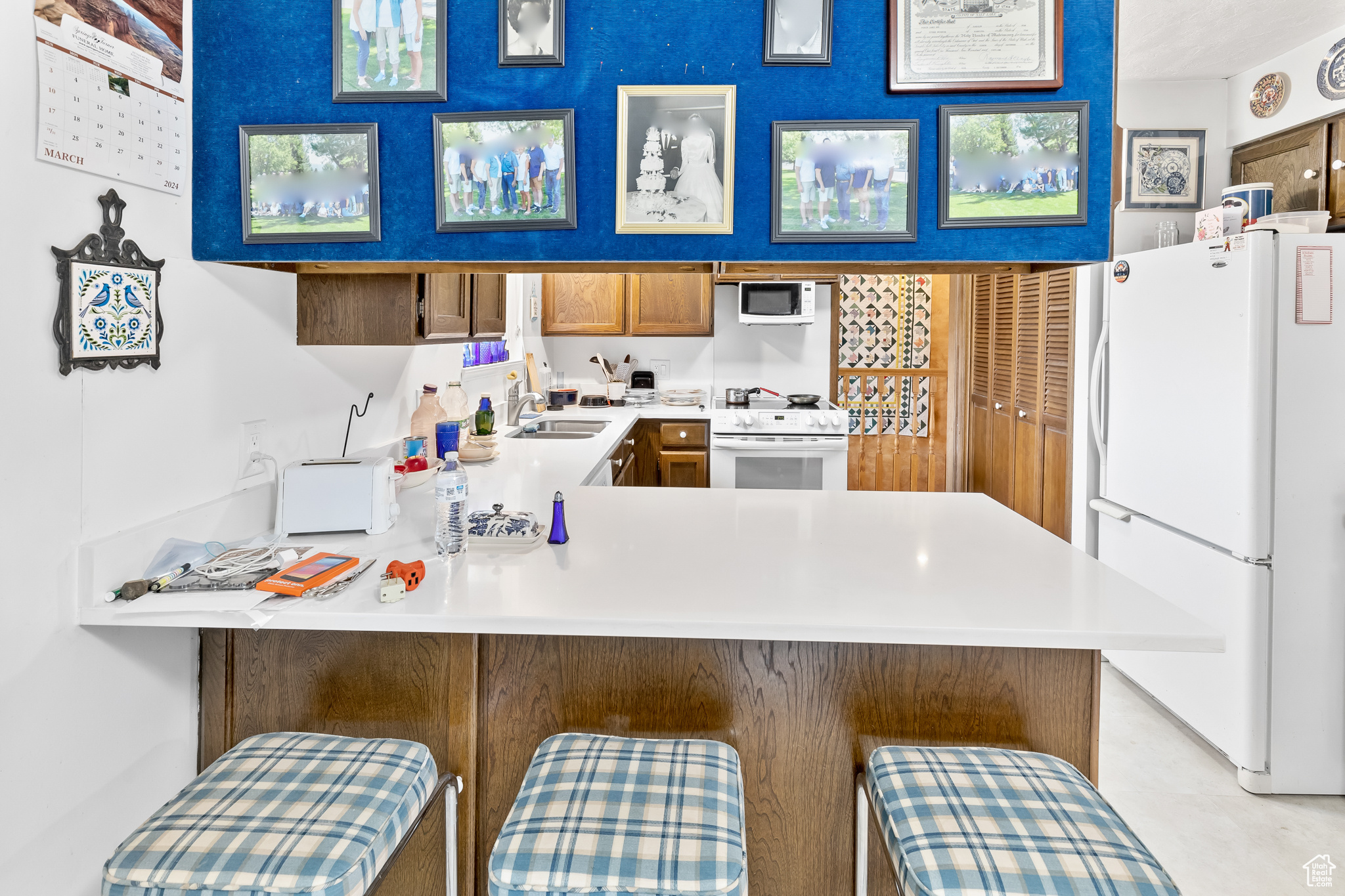 Kitchen with sink, white appliances, kitchen peninsula, and a kitchen breakfast bar