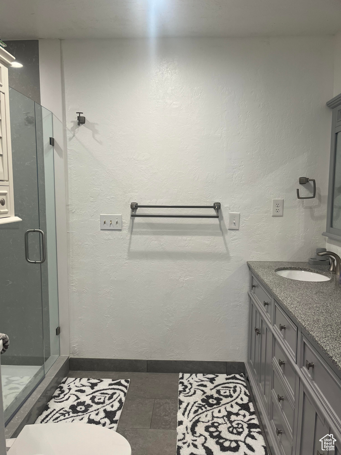Bathroom featuring vanity with double sinks, a shower with shower door, and tile floors