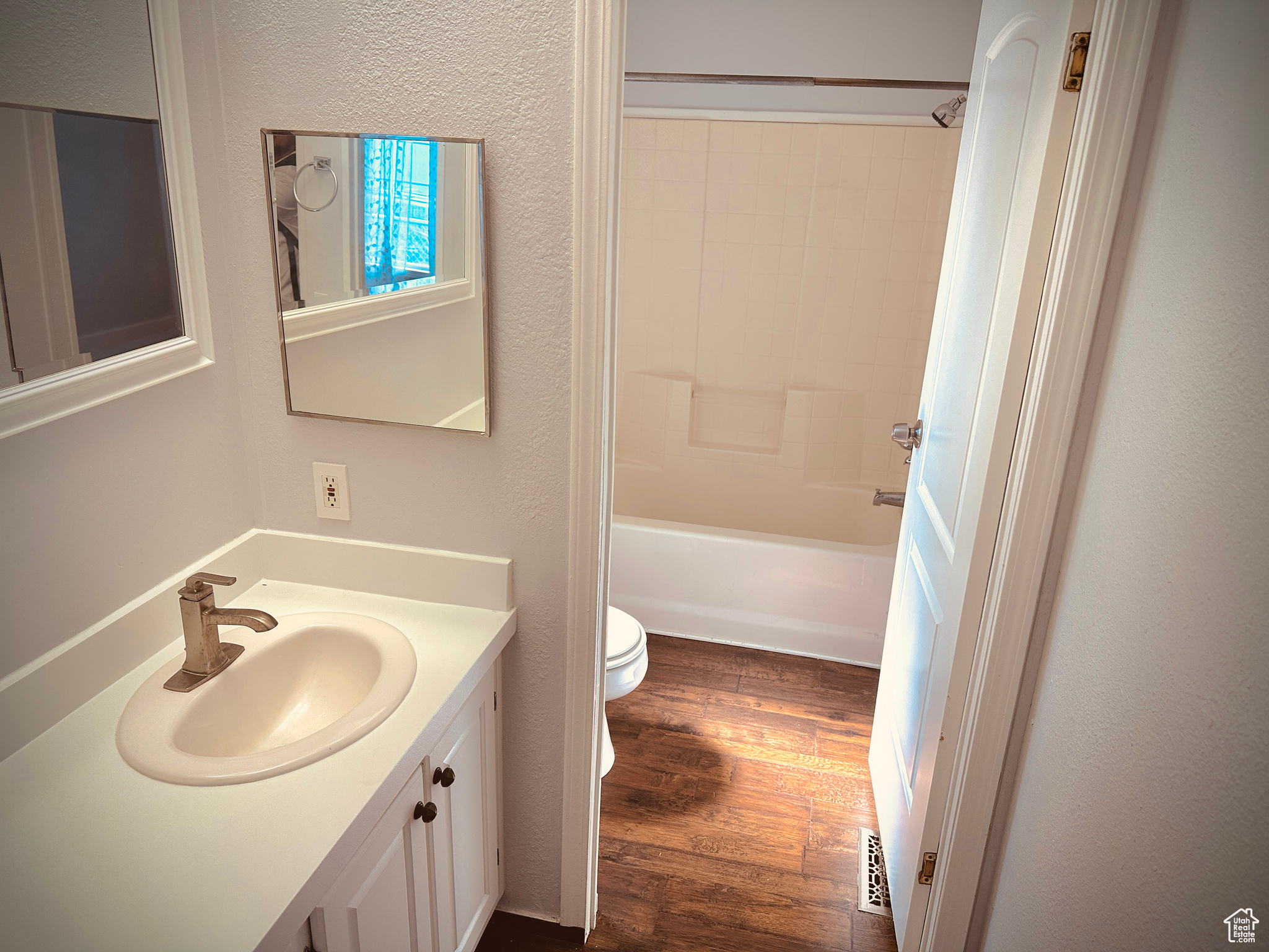 Full bathroom with toilet, bathing tub / shower combination, oversized vanity, and hardwood / wood-style flooring