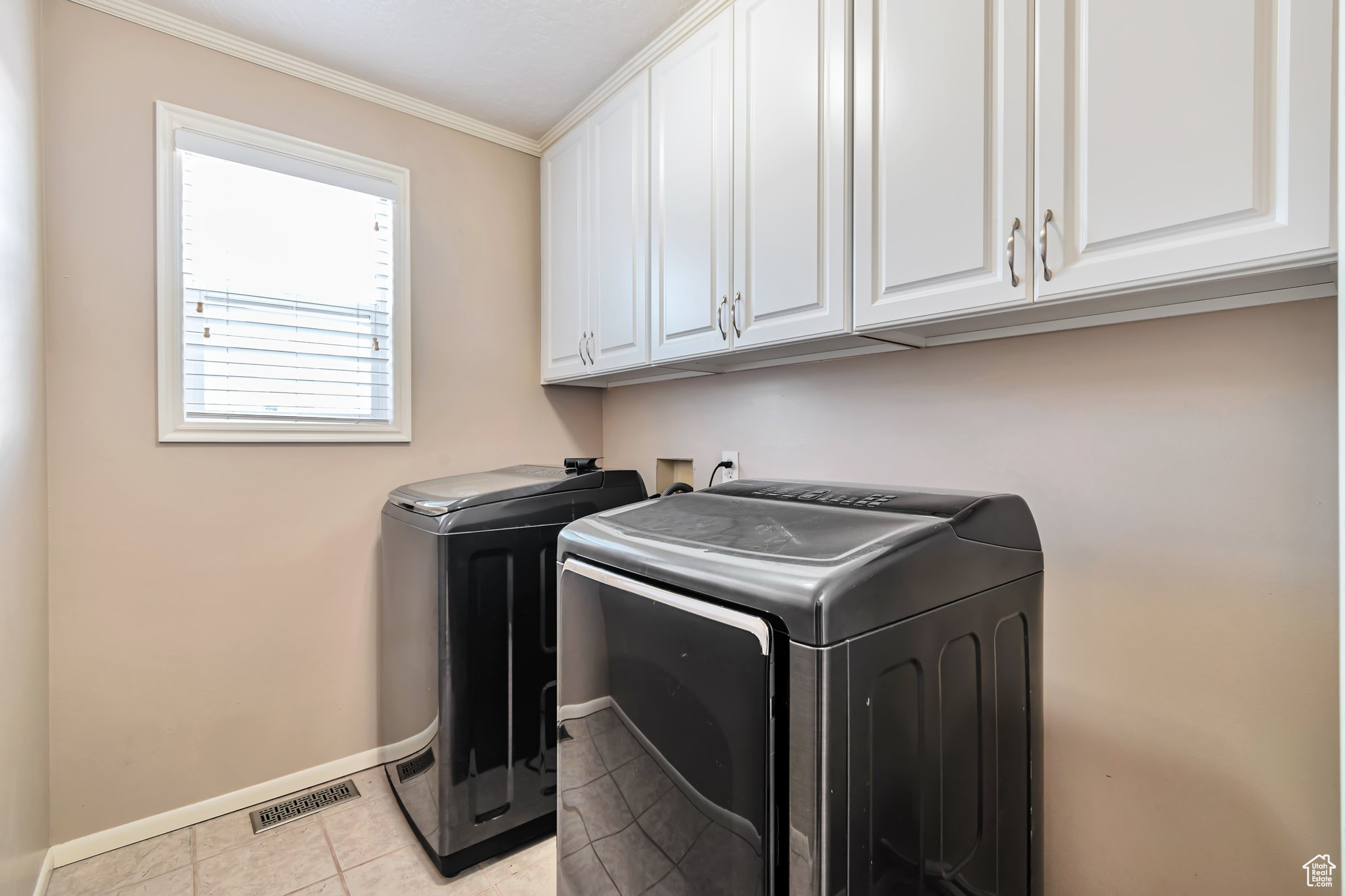 Laundry room featuring washer and dryer (gas and electric hookup), top cabinets for storage, and light tile flooring