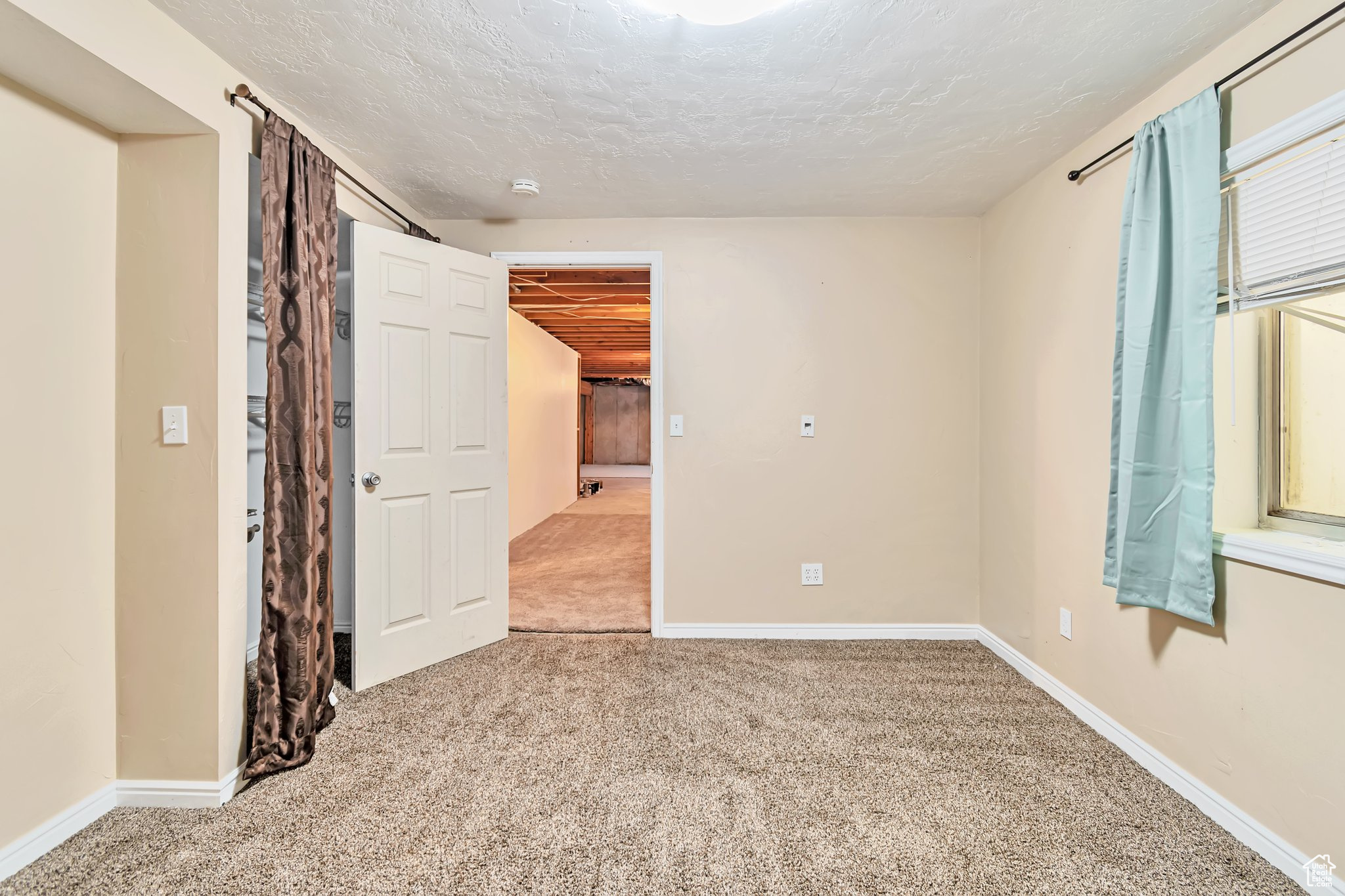 carpeted room with window, closet, and textured ceiling.