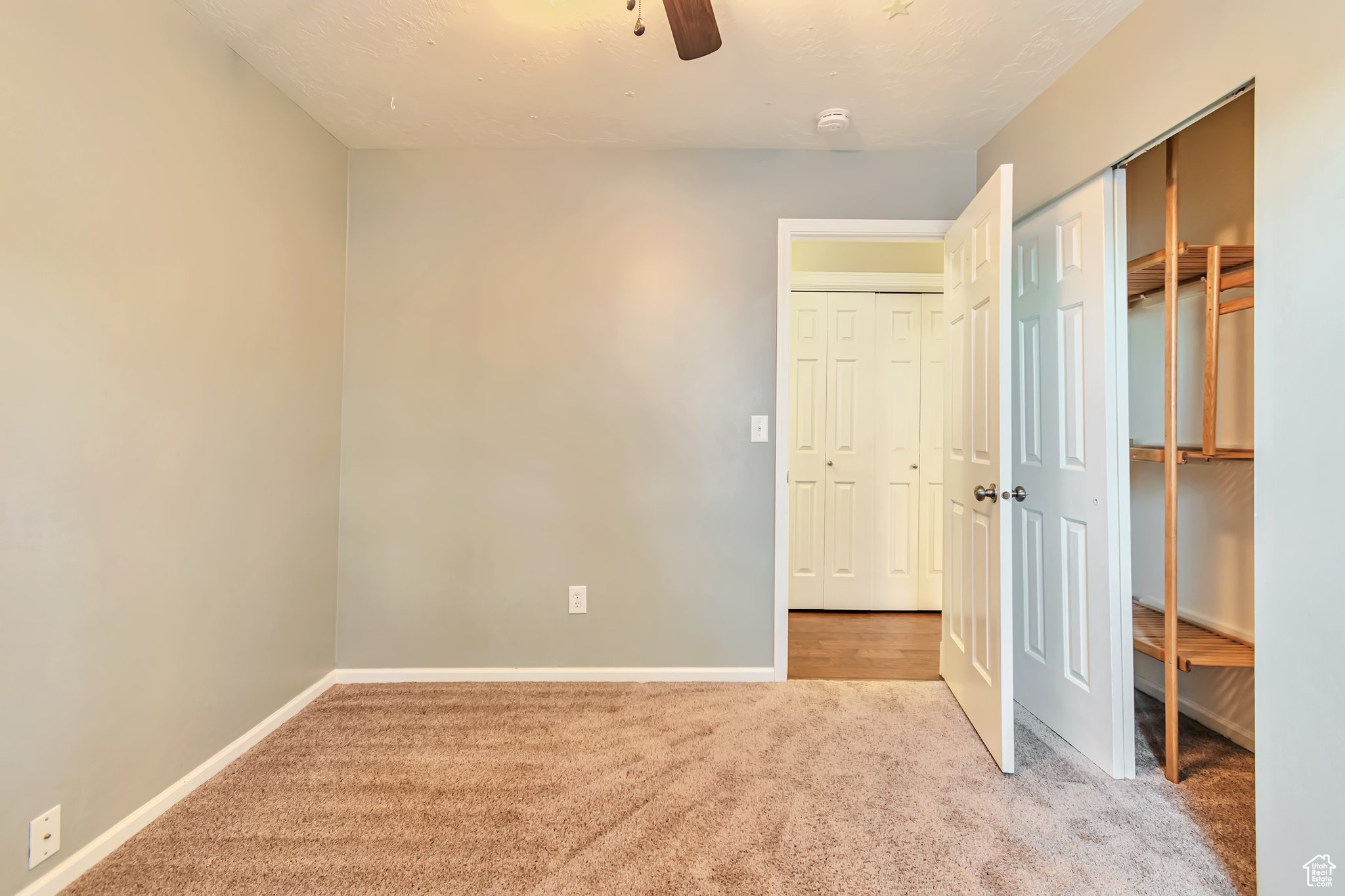 bedroom featuring light carpet, closet with shelving, and ceiling fan