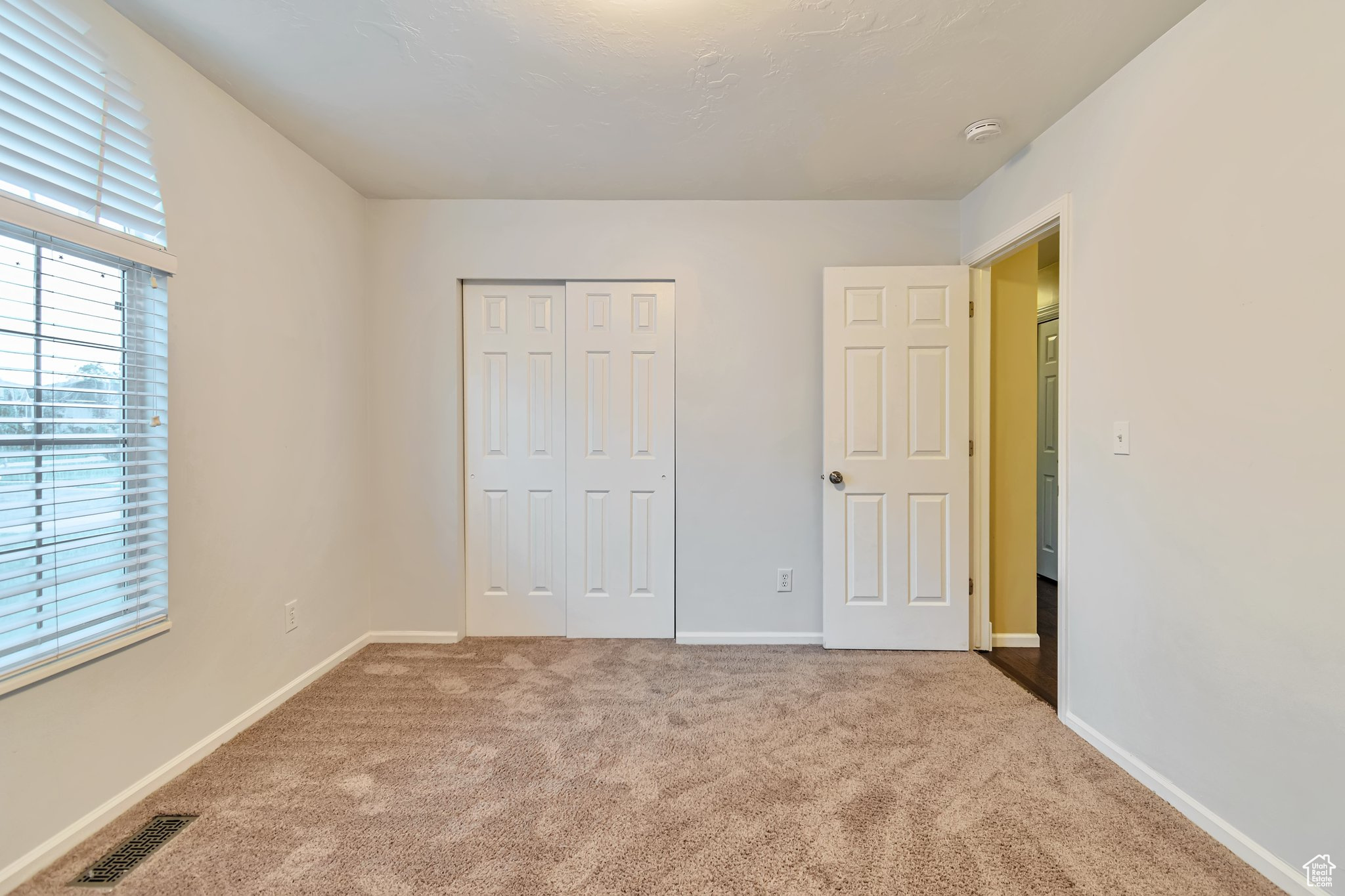 large bedroom with a closet, light carpet, and XL window.