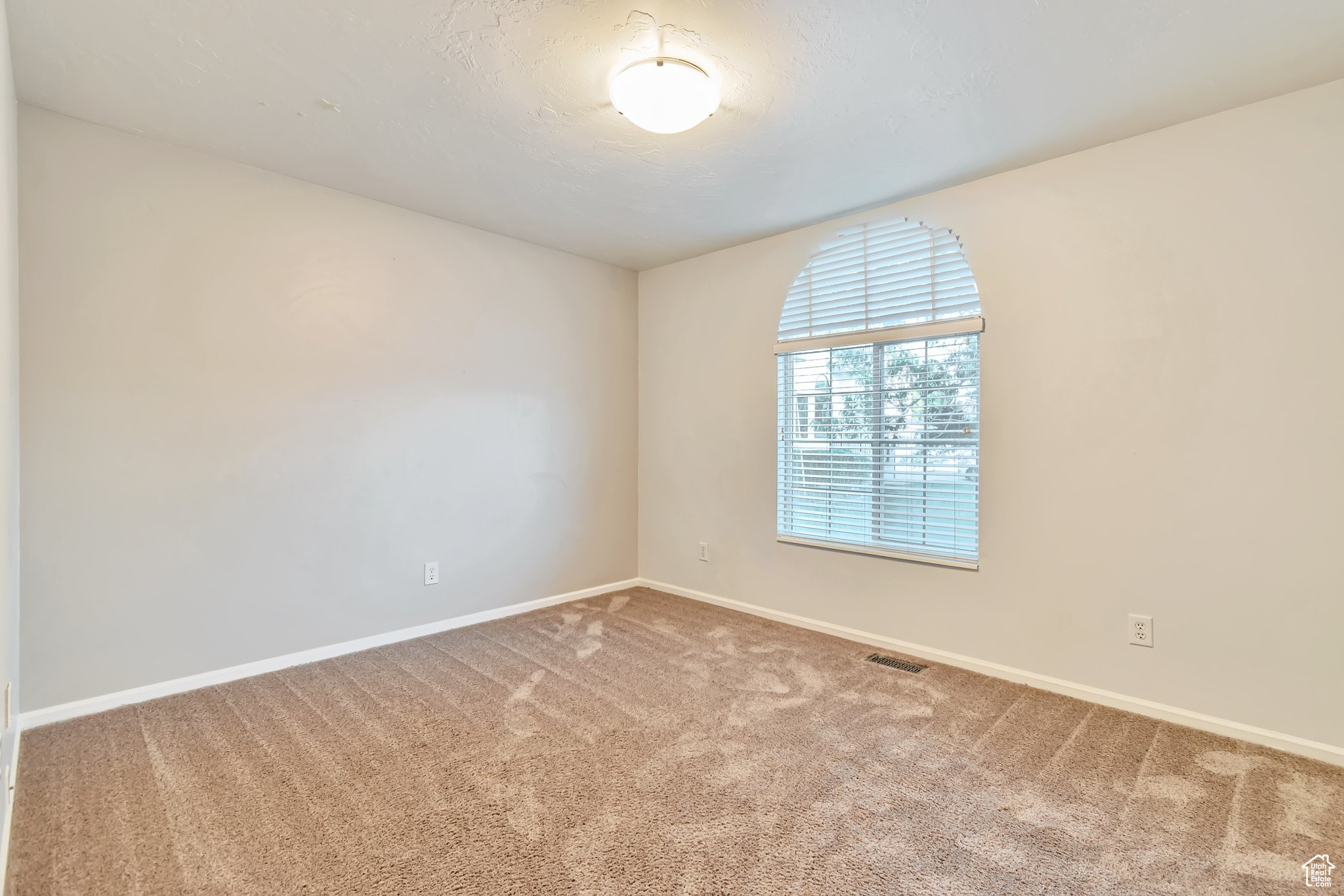 Large bedroom featuring carpet floors, XL window with blinds.