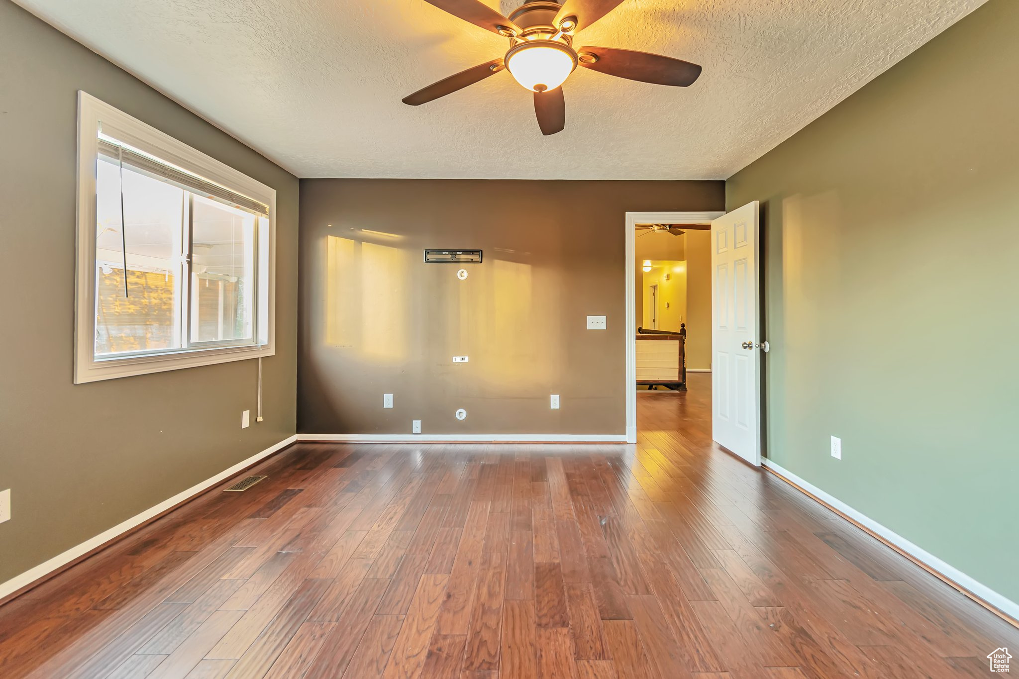 great room featuring a textured ceiling, dark hardwood / wood-style flooring, door and ceiling fan