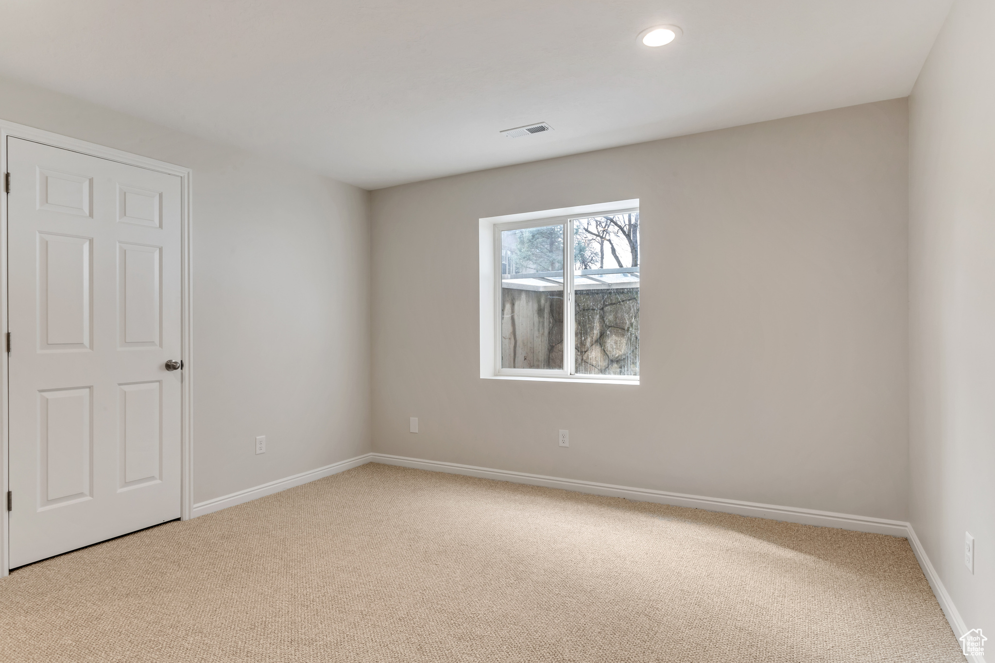 One of two bedrooms in basement with large window and new carpet