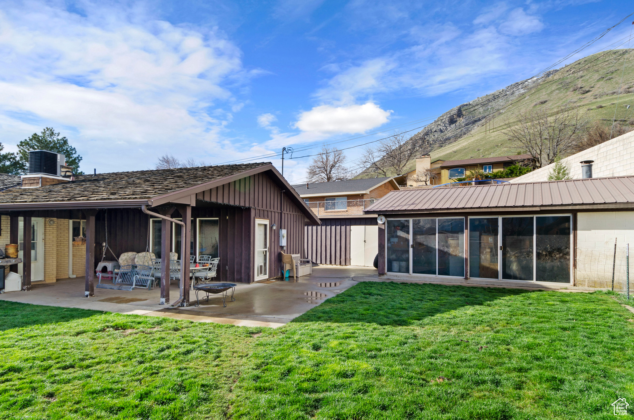 Back of property with a mountain view, lawn, patio, and a workshop.
