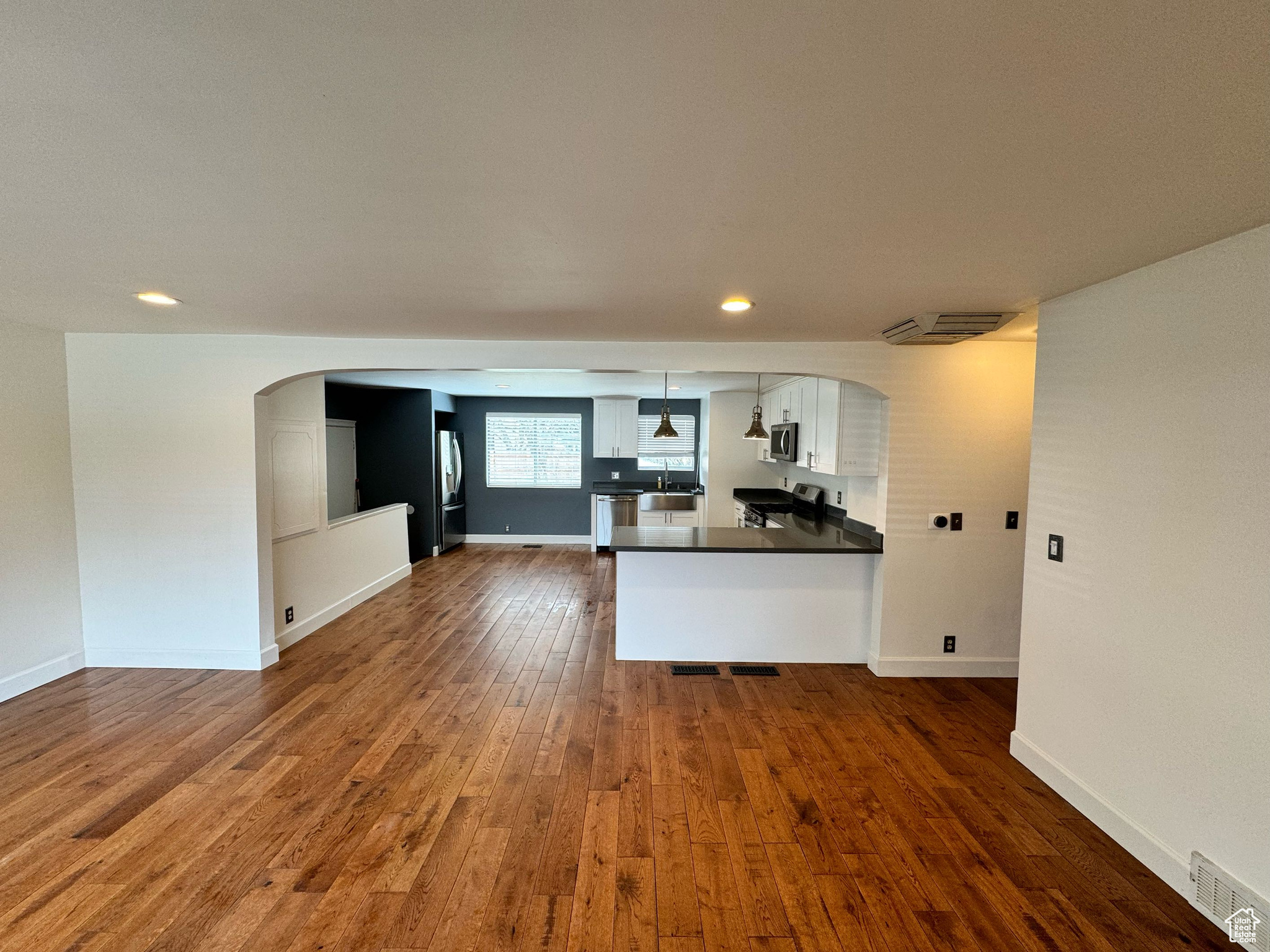 Kitchen featuring pendant lighting, white cabinetry, kitchen peninsula, and dark hardwood / wood-style floors