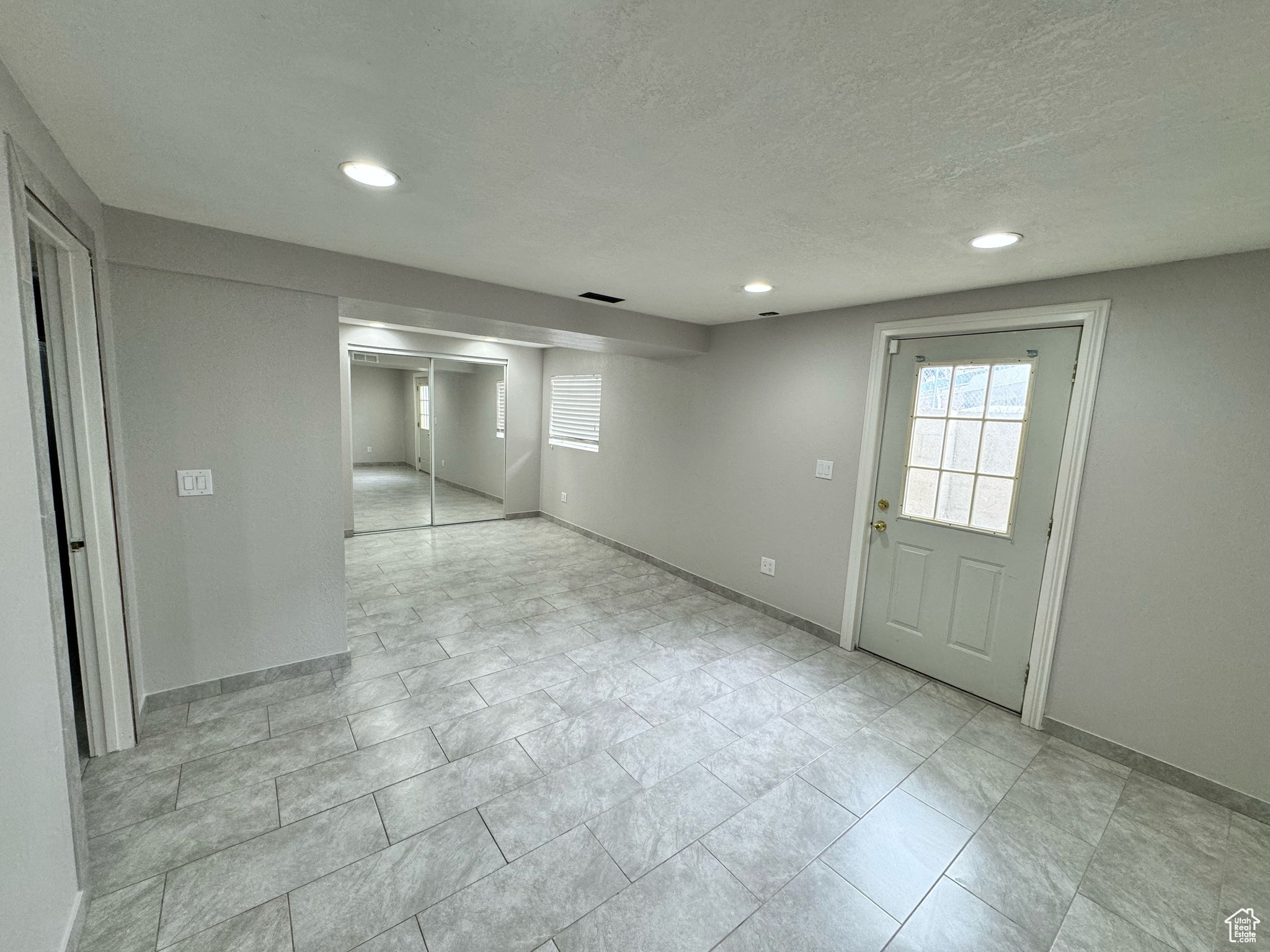 Empty room featuring a textured ceiling and light tile floors