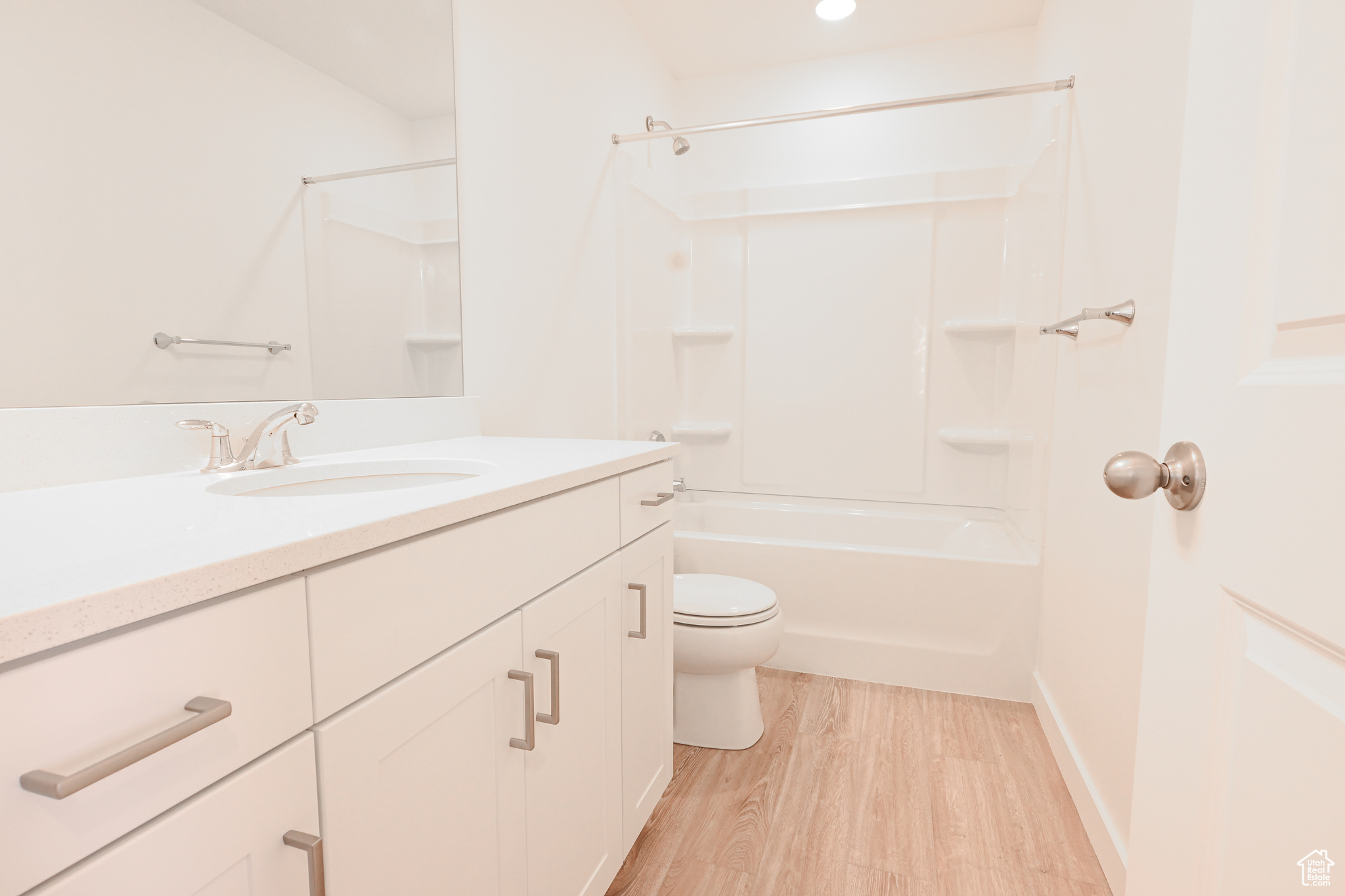 Full bathroom with hardwood / wood-style flooring, vanity,  shower combination, and toilet