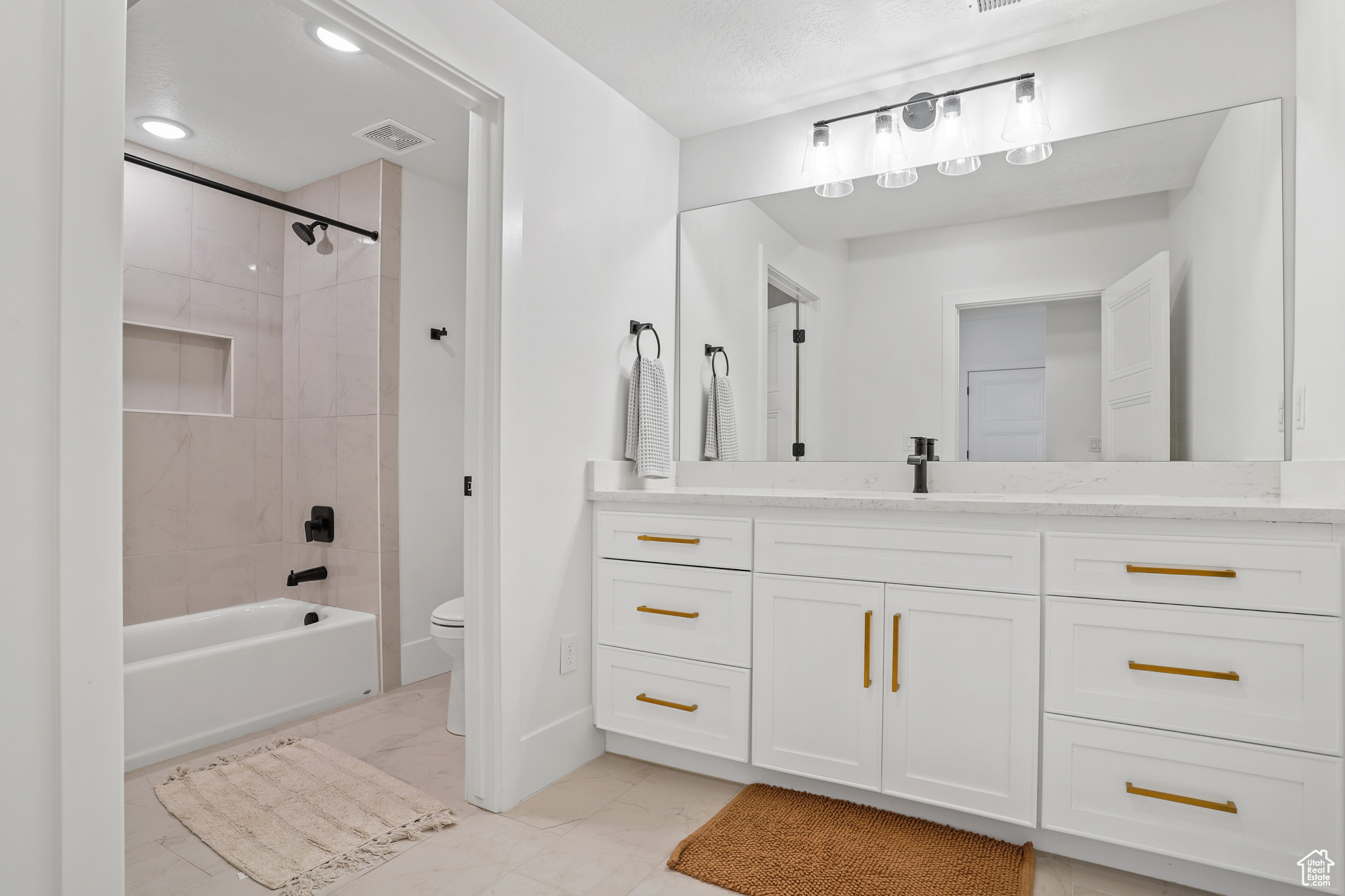 Full bathroom with tile flooring, tiled shower / bath combo, vanity, and toilet