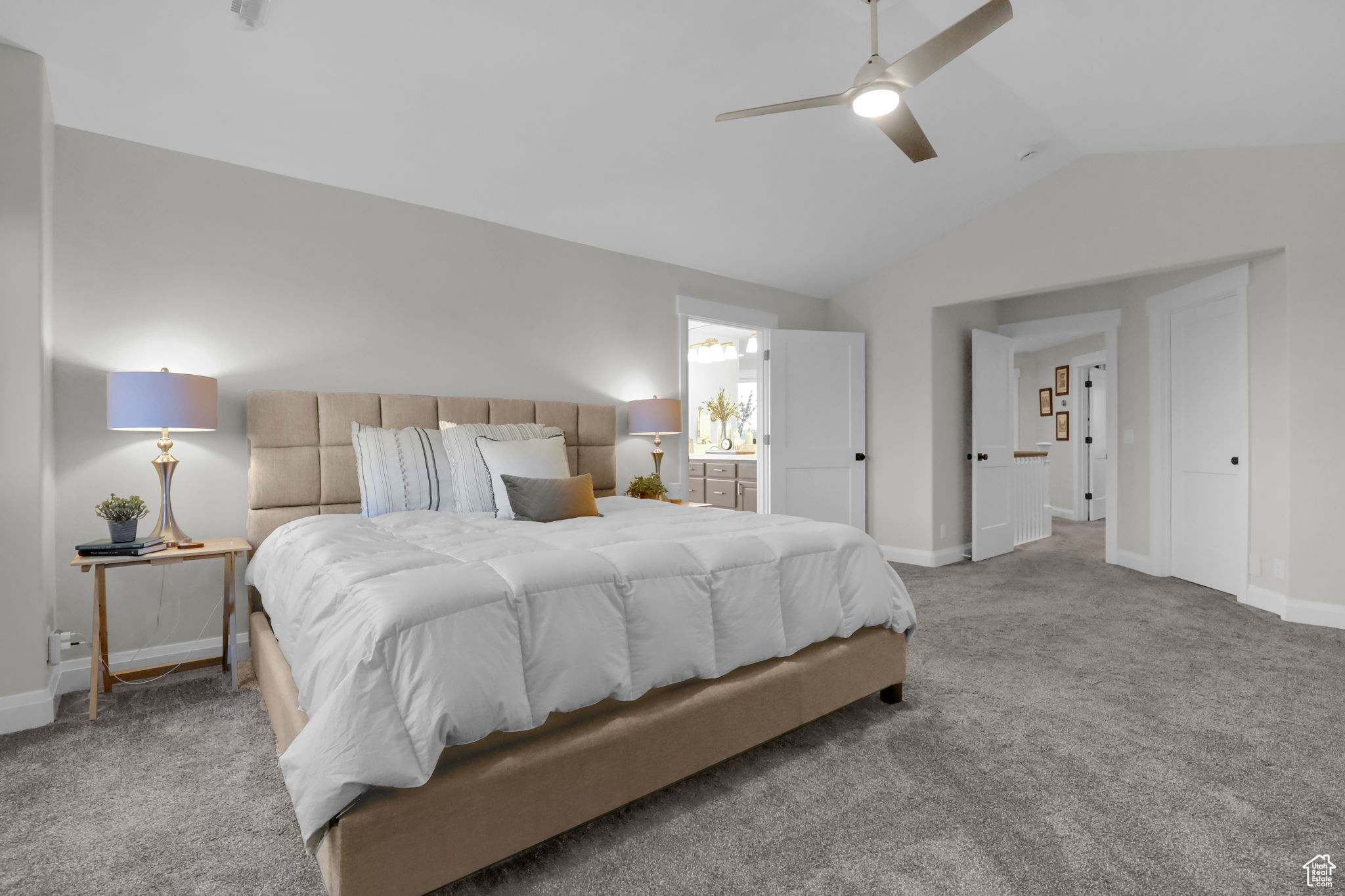 Carpeted bedroom with ceiling fan, vaulted ceiling, and connected bathroom