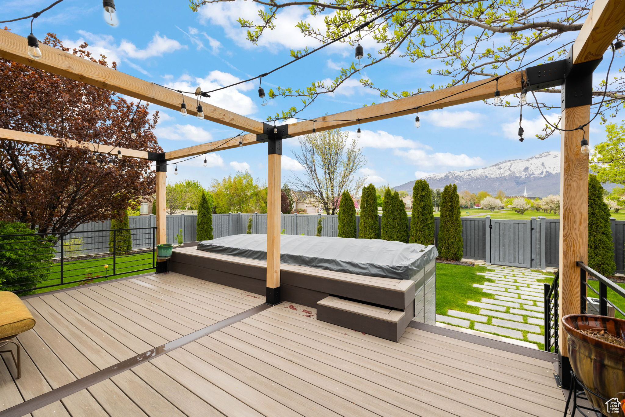 Wooden deck featuring a covered hot tub, a mountain view, and a yard