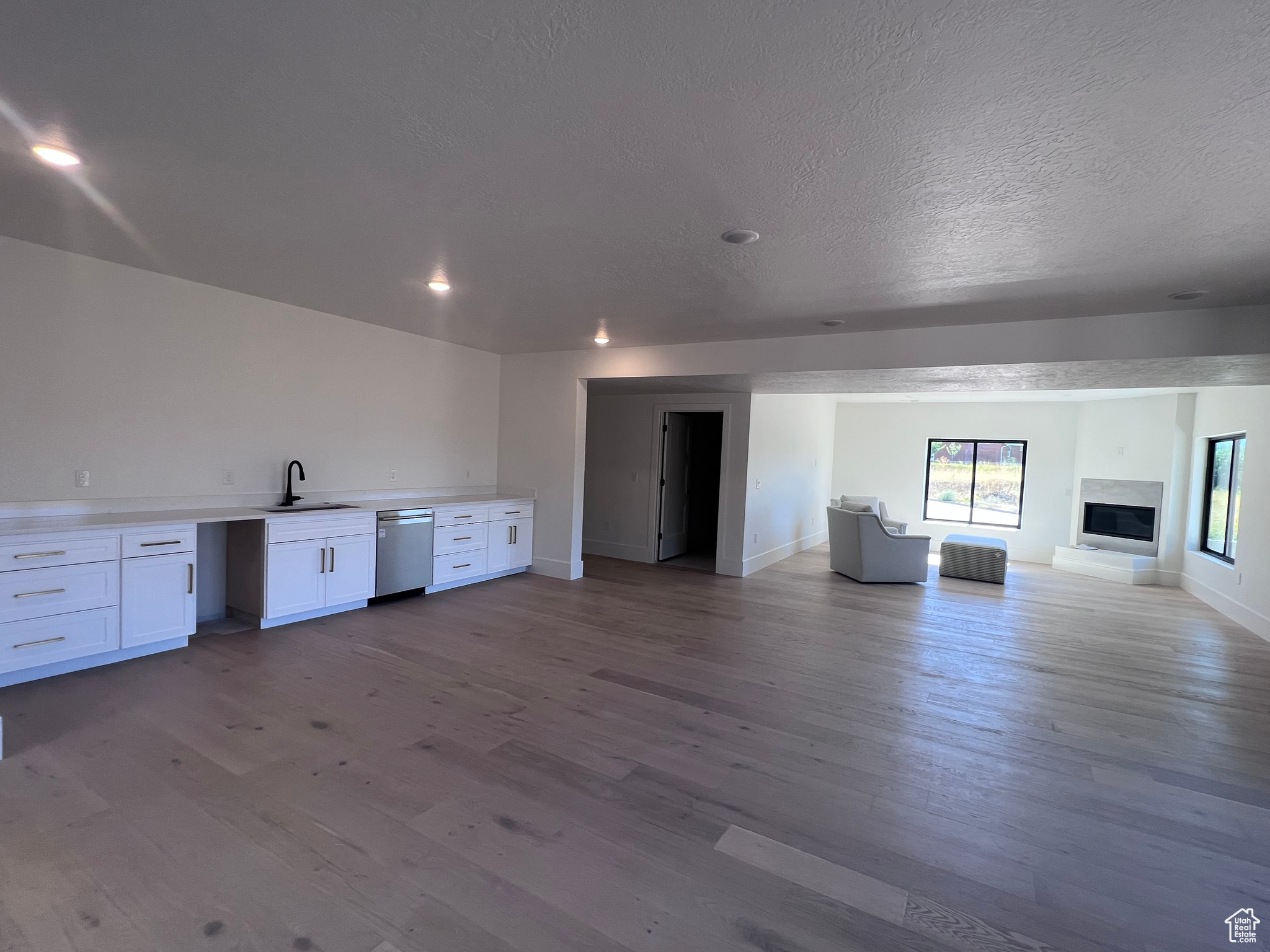 Unfurnished living room with light hardwood / wood-style flooring, a textured ceiling, and sink
