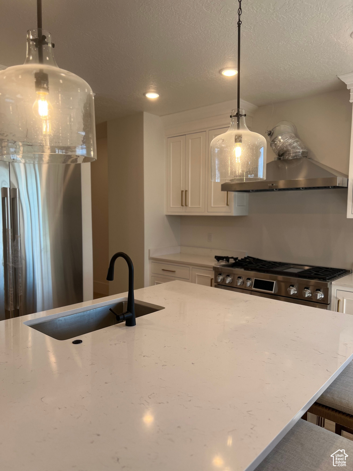 Kitchen featuring white cabinets, hanging light fixtures, and light stone counters