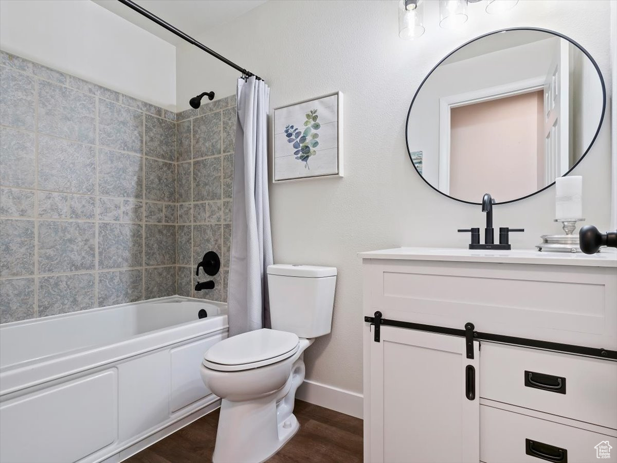 Full bathroom with shower / bath combo, toilet, wood-type flooring, and vanity