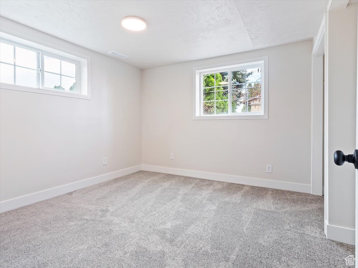 Empty room with light carpet and a textured ceiling