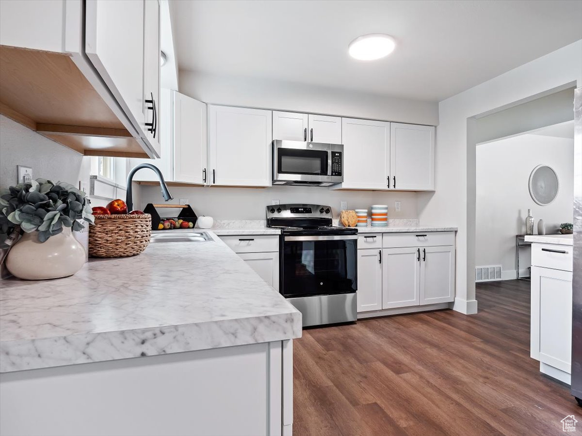 Kitchen featuring dark hardwood / wood-style floors, white cabinetry, appliances with stainless steel finishes, and sink