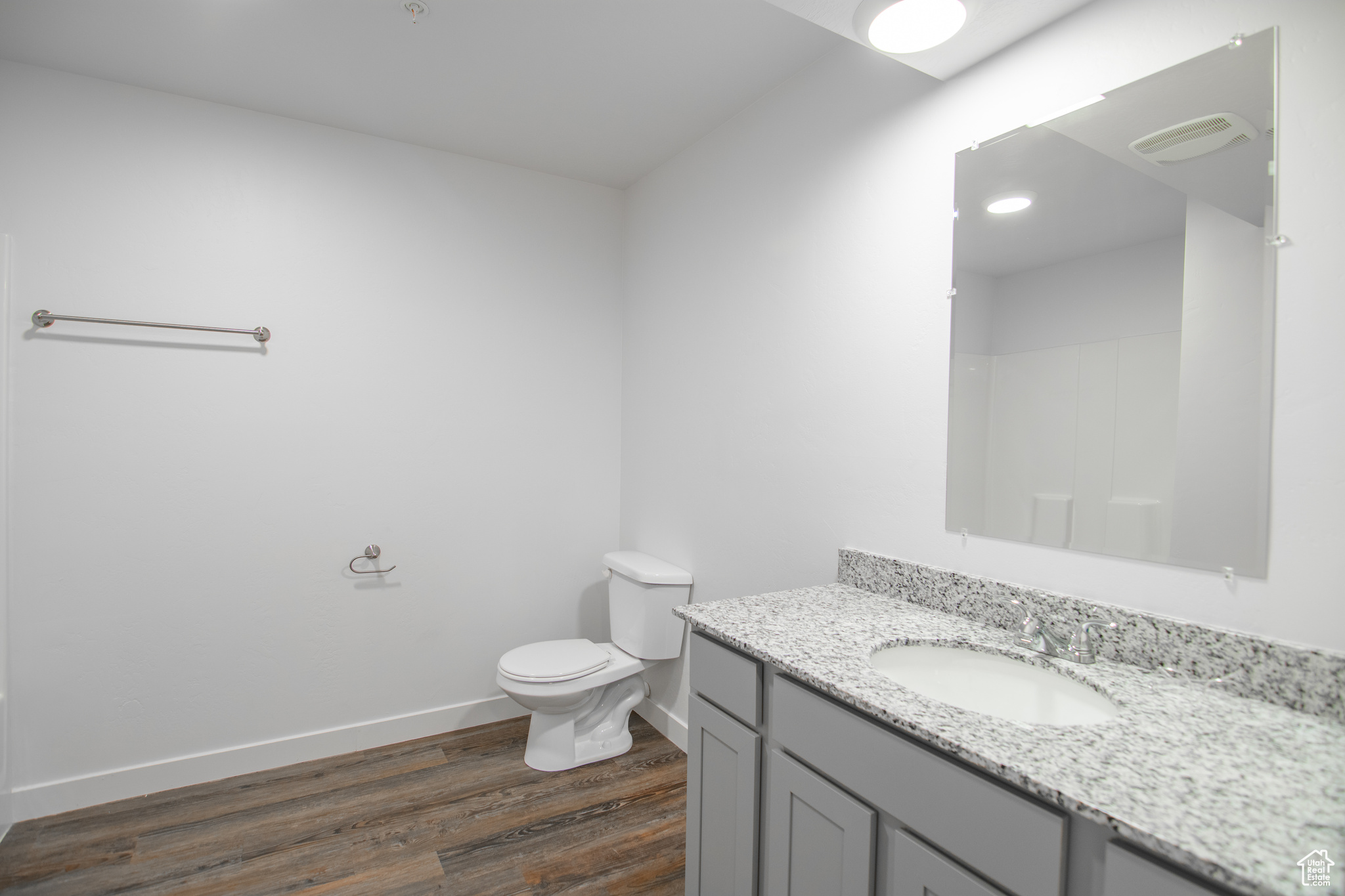 Bathroom with hardwood / wood-style floors, toilet, and large vanity