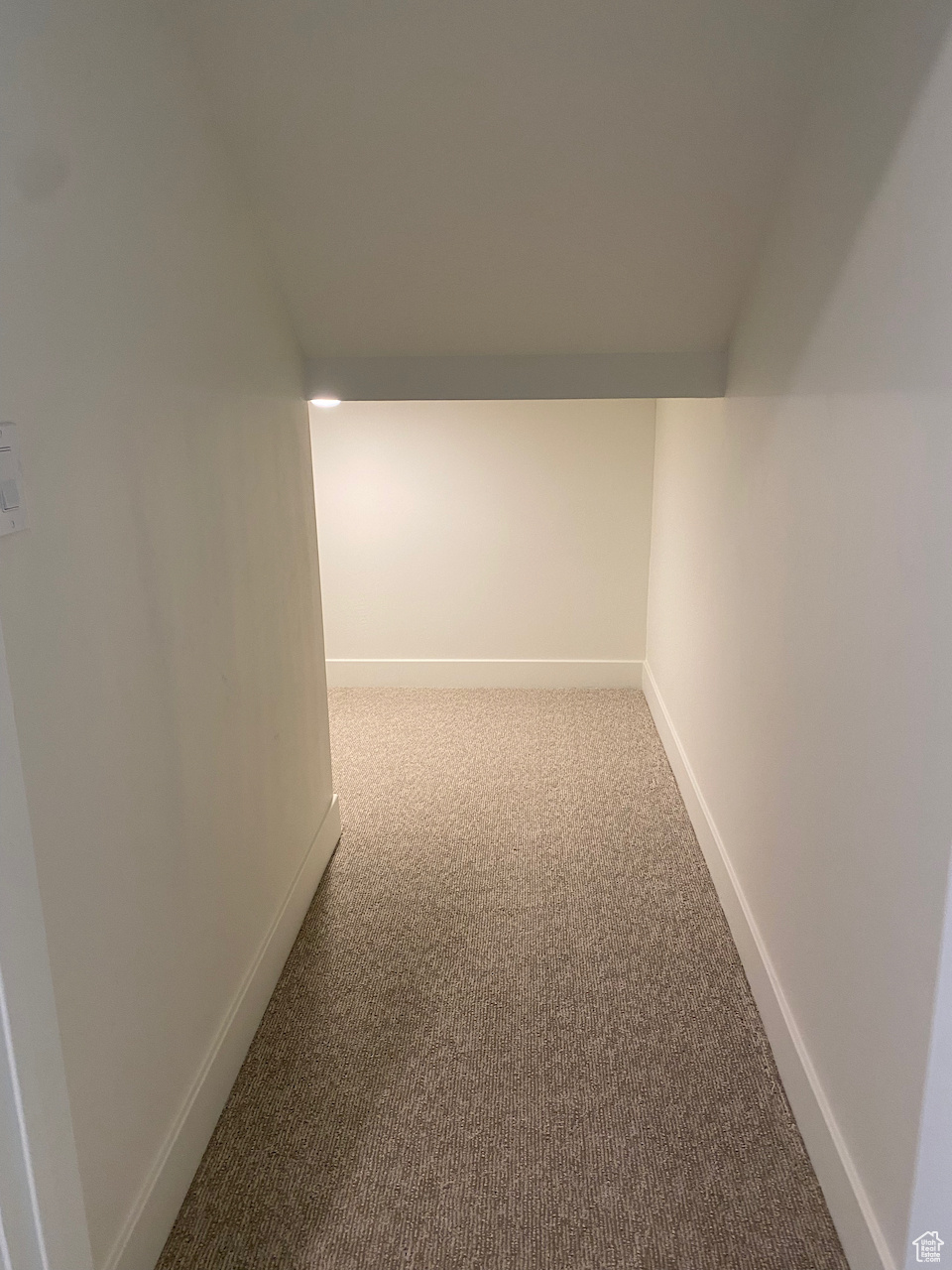 Hallway featuring light colored carpet