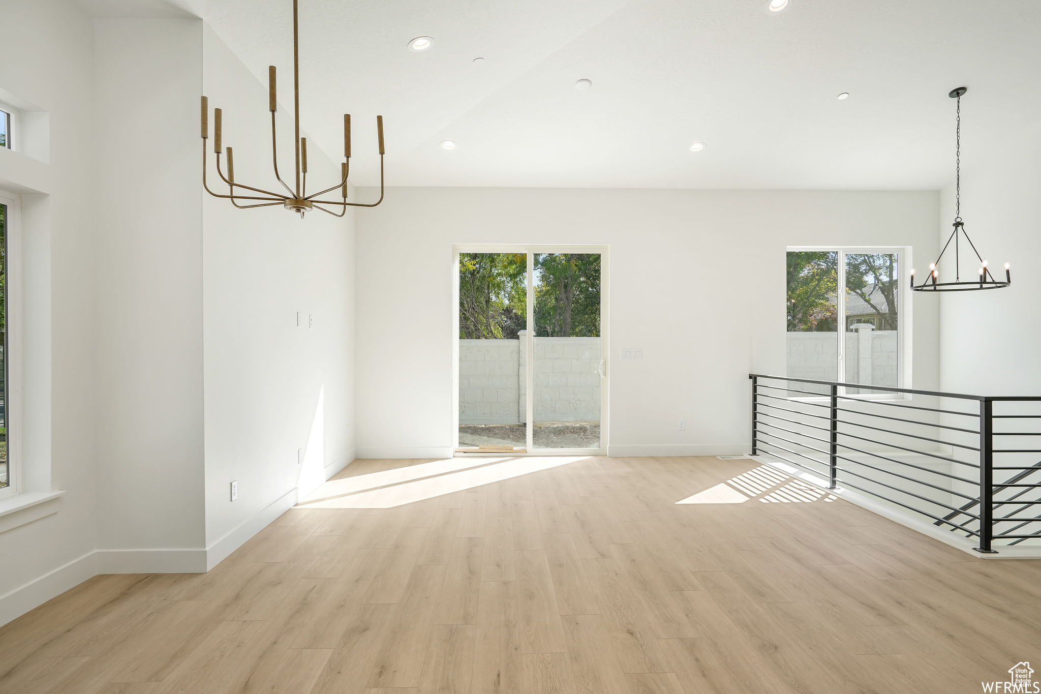 Great room featuring an inviting chandelier, a wealth of natural light, and light hardwood / wood-style floors