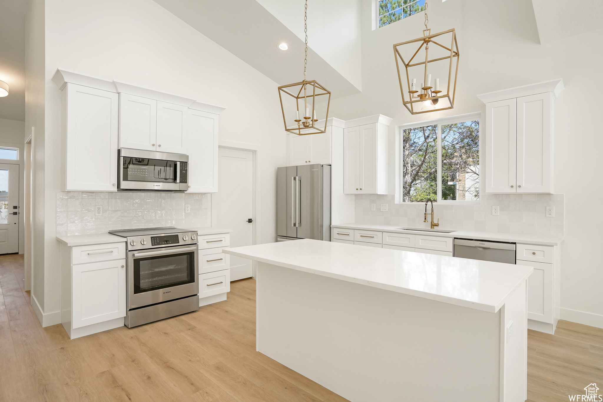 Kitchen with tasteful backsplash, white cabinets, stainless steel appliances, and a kitchen island