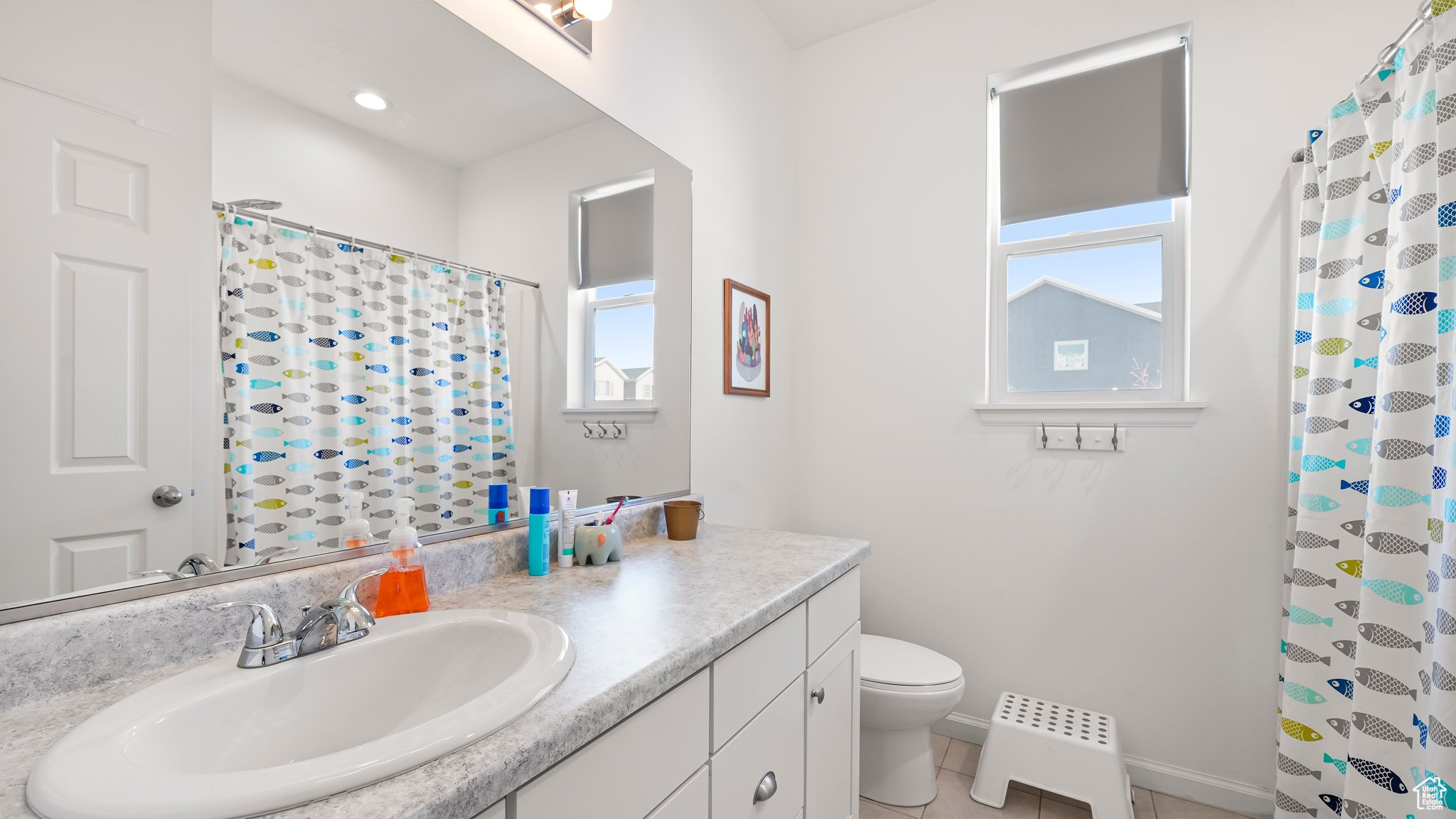 Bathroom with vanity with extensive cabinet space, tile floors, and toilet