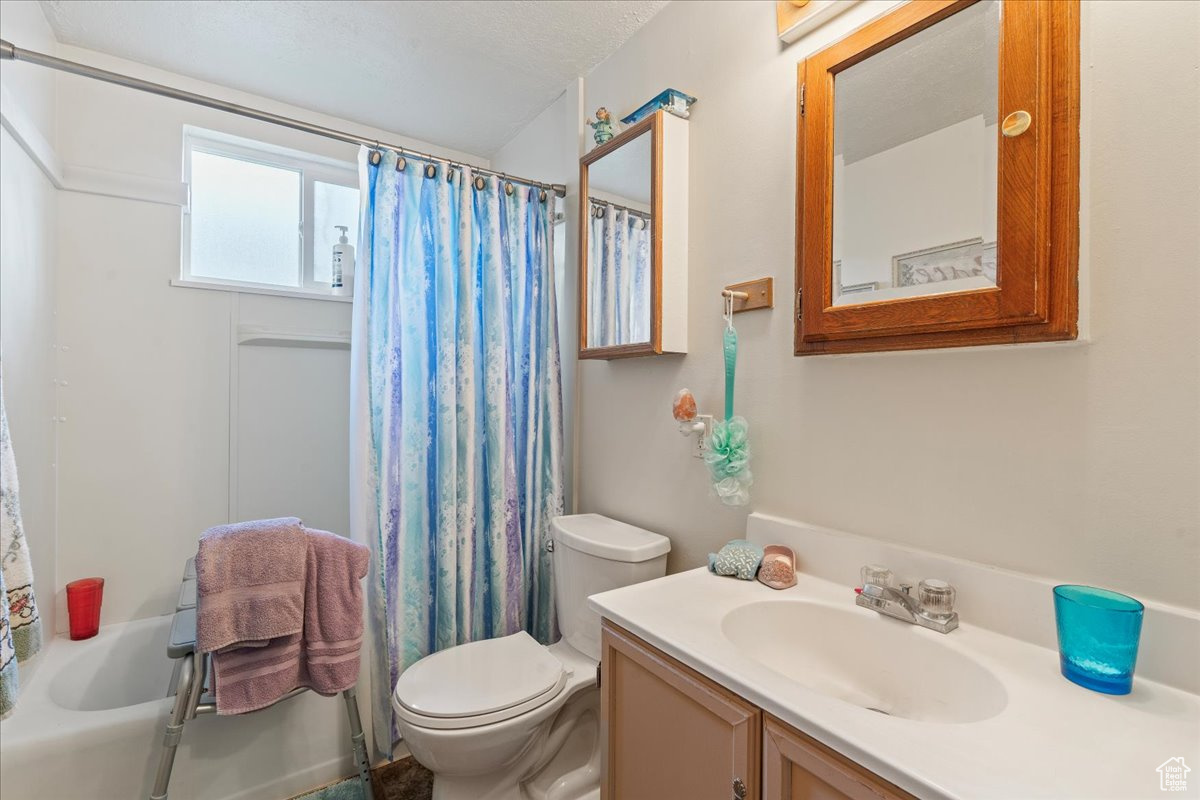 Full bathroom featuring toilet, large vanity, and shower / tub combo